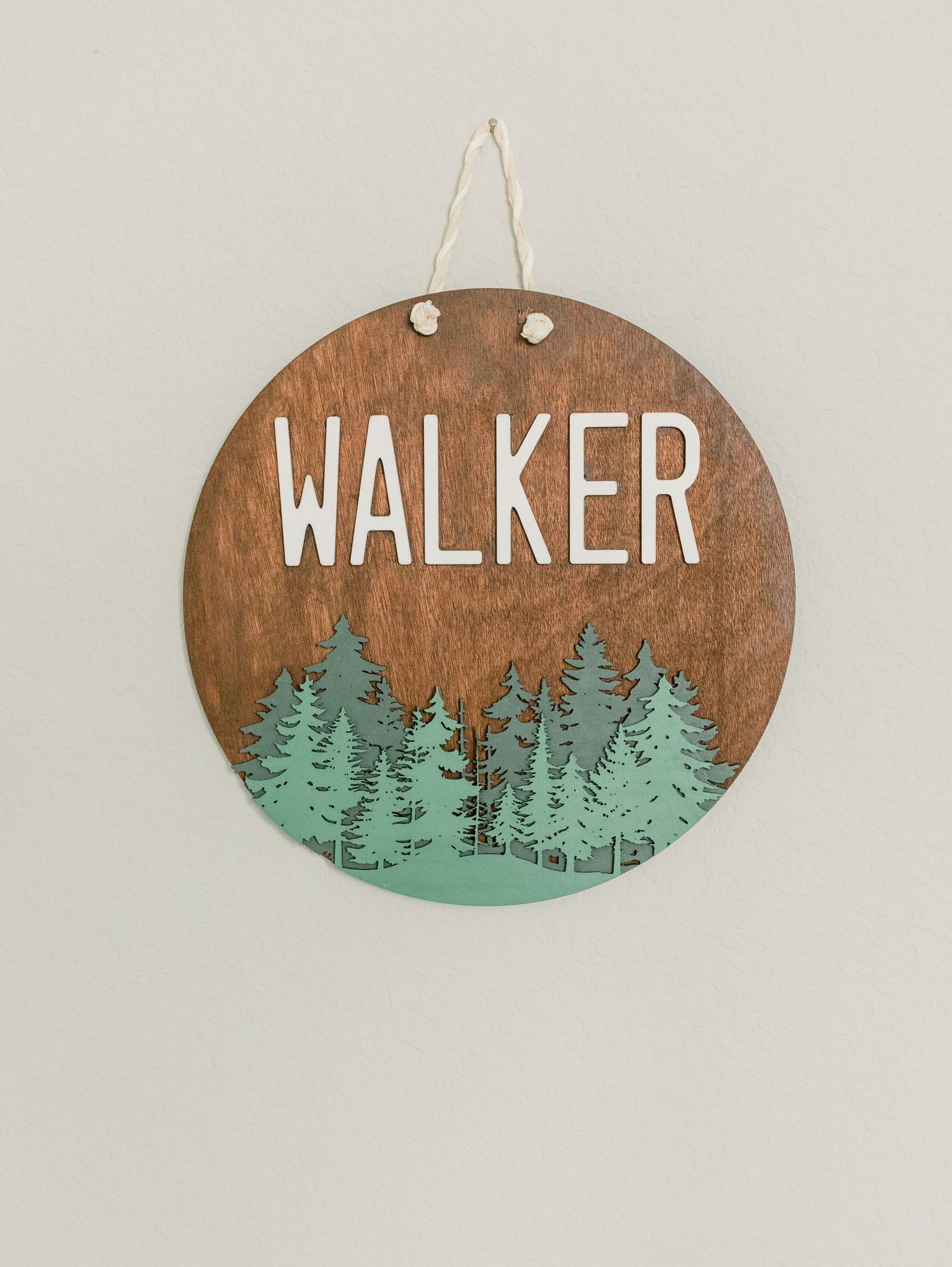 Round wooden wall sign with forest design displaying the name 'Walker' in white lettering.