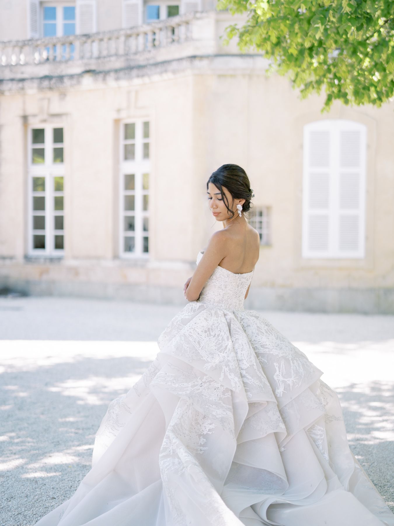 Ethereal wedding gown with layered skirt detail against classic French architecture backdrop.