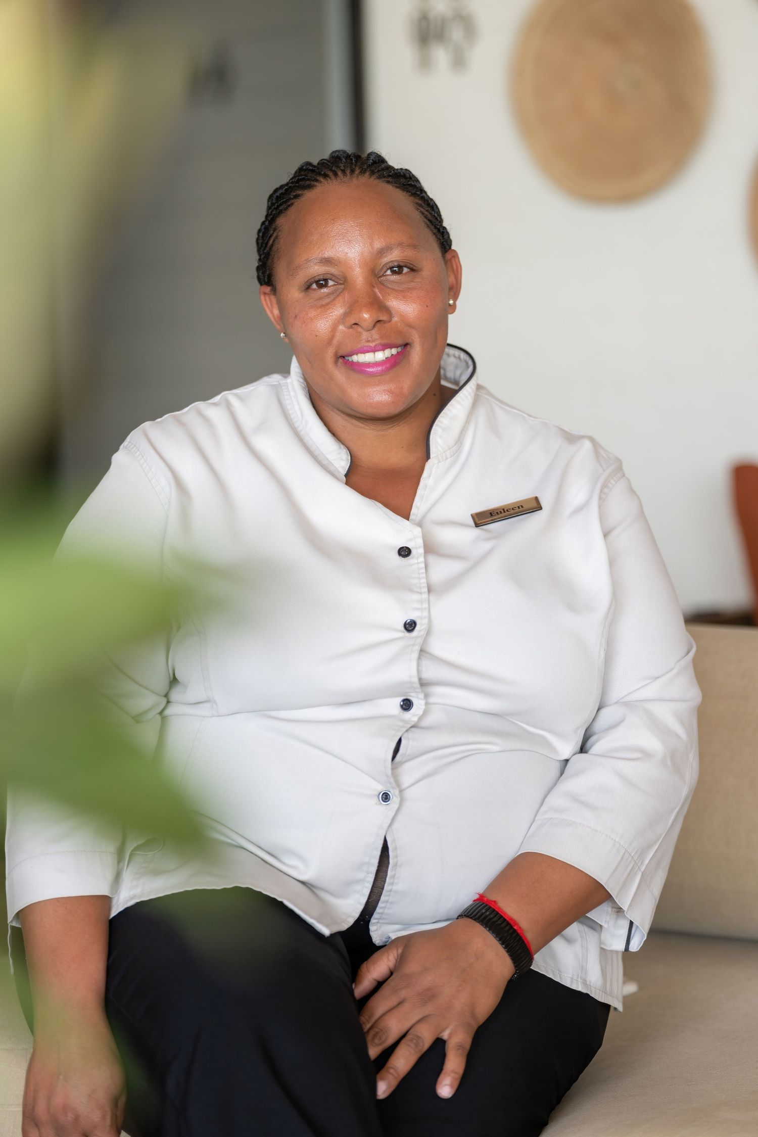 Staff member in crisp white chef uniform sitting in professional portrait setting.