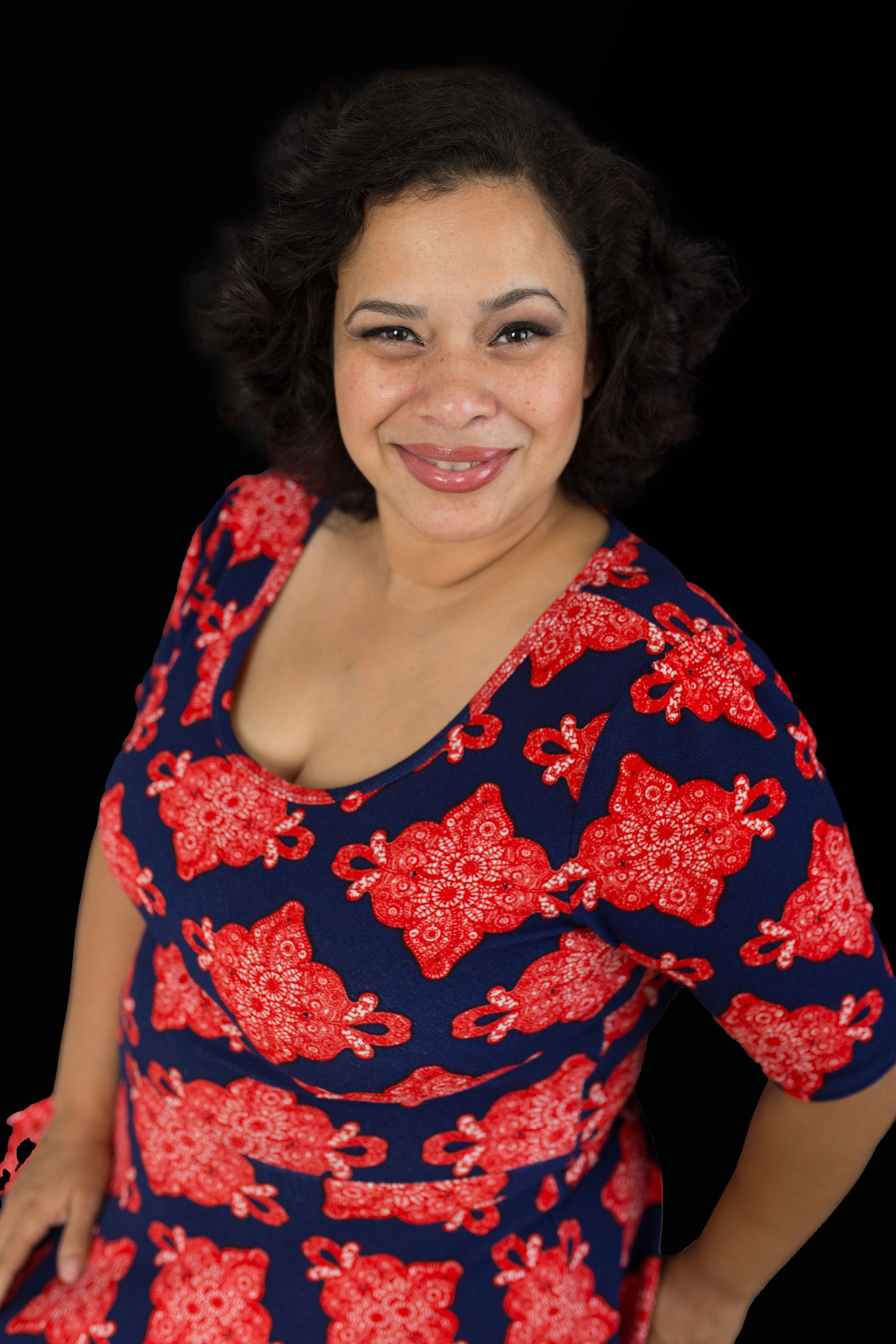 Portrait of person wearing navy and red patterned dress against dark background.
