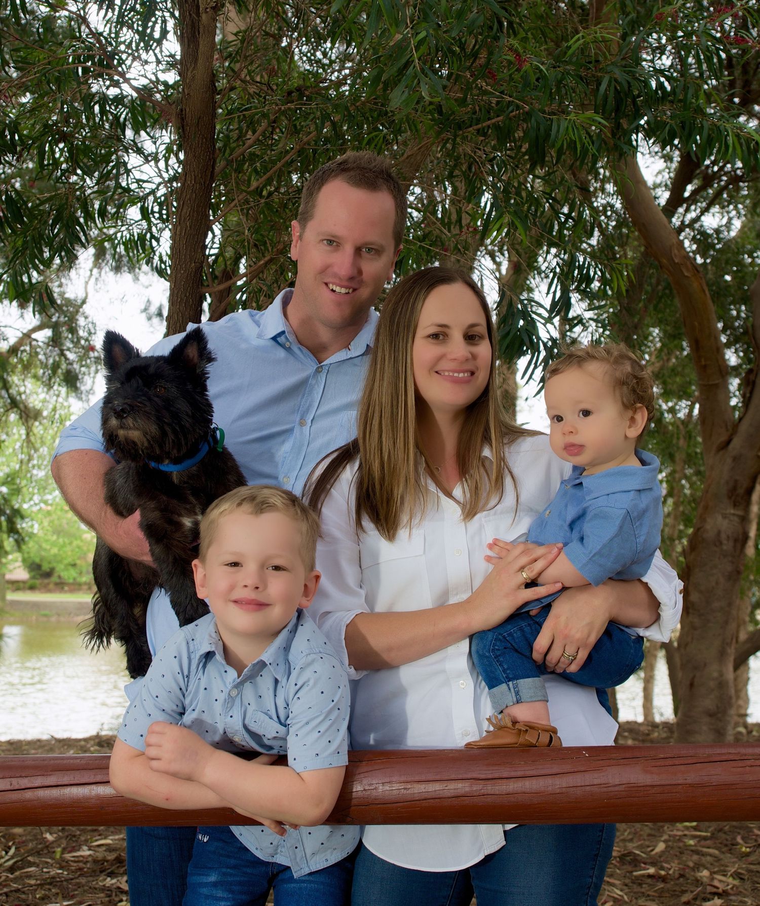 family portrait of a mother father family dog and two young boys at a park
