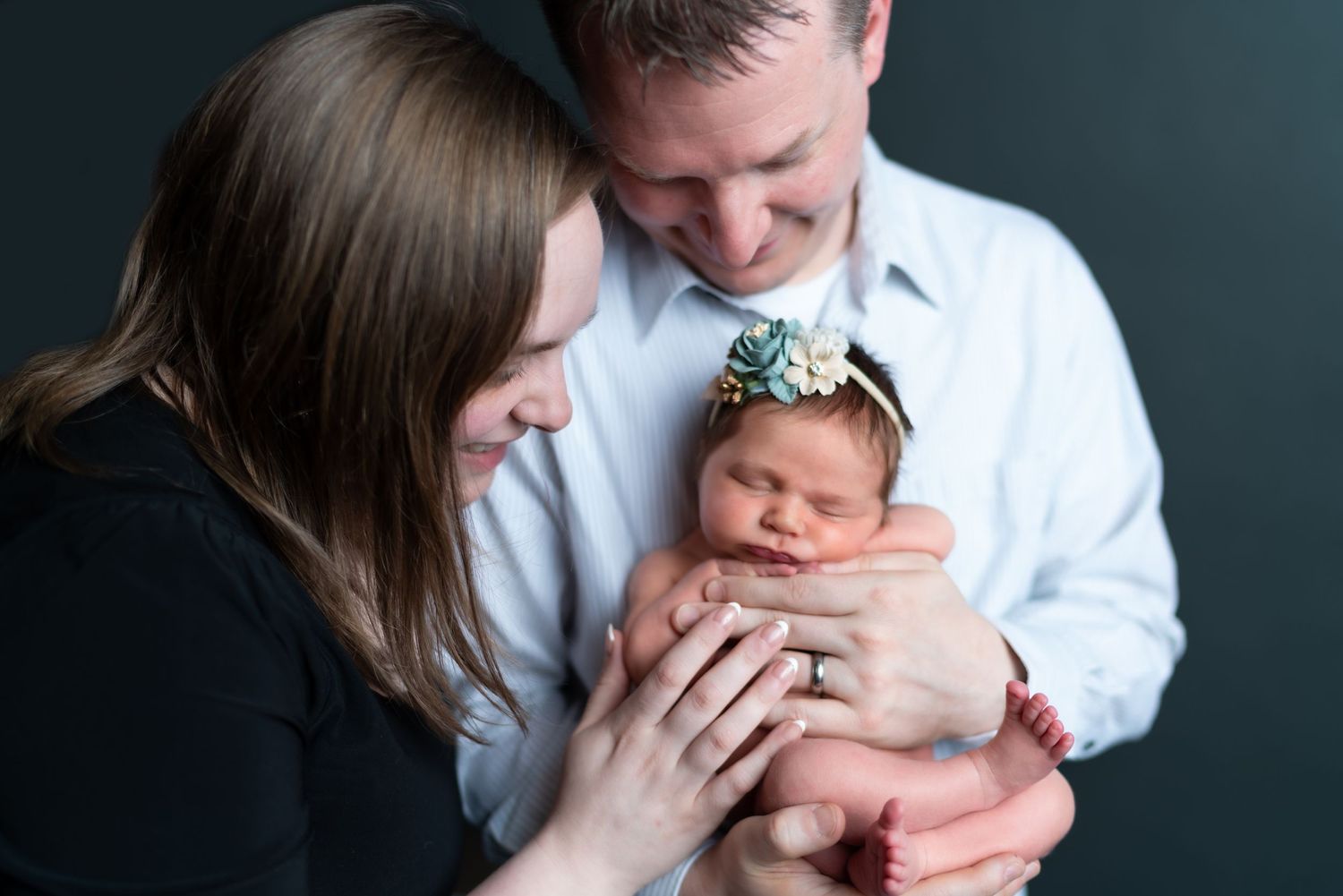 Intimate family portrait against dark background in studio setting.