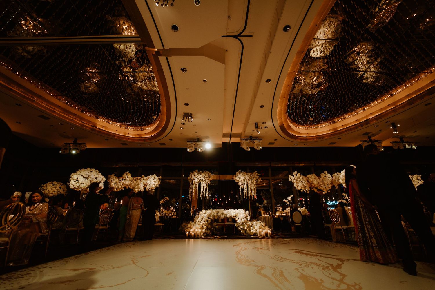 Luxurious wedding reception venue with dramatic lighting and floral ceiling installations.