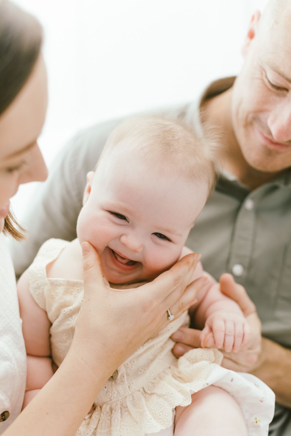Joyful moment captured as baby giggles while being held by family members.