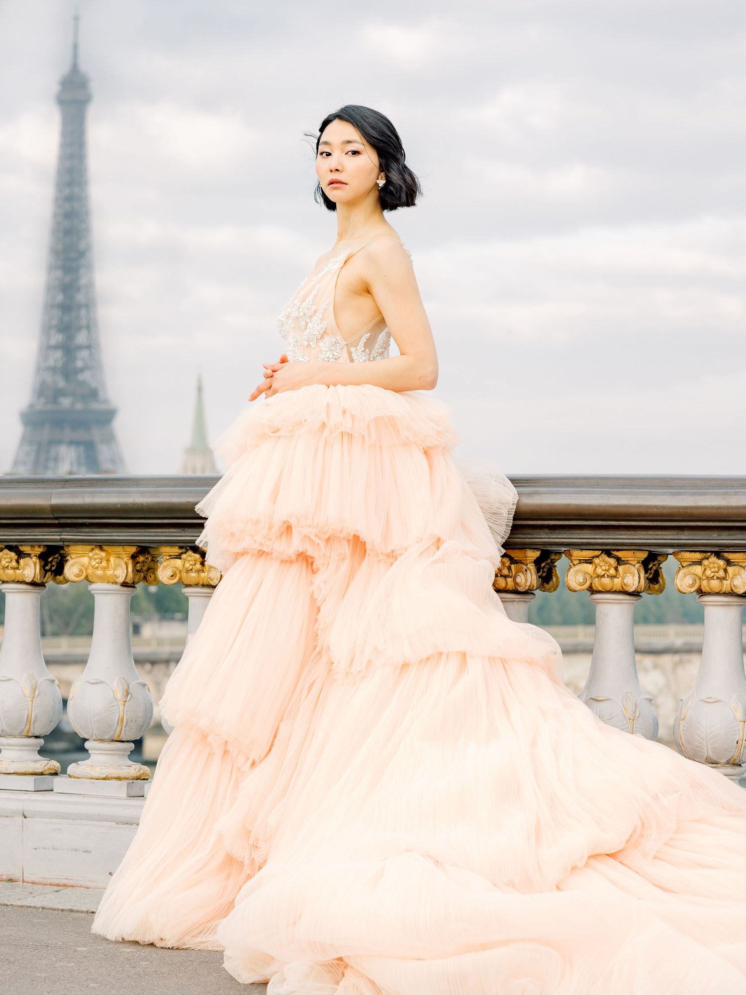 Romantic peach tulle gown photographed against Paris skyline with Eiffel Tower in background.