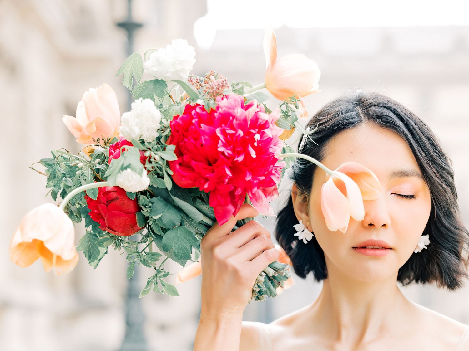 Romantic bridal bouquet with vibrant red peonies, peach roses and lush greenery.