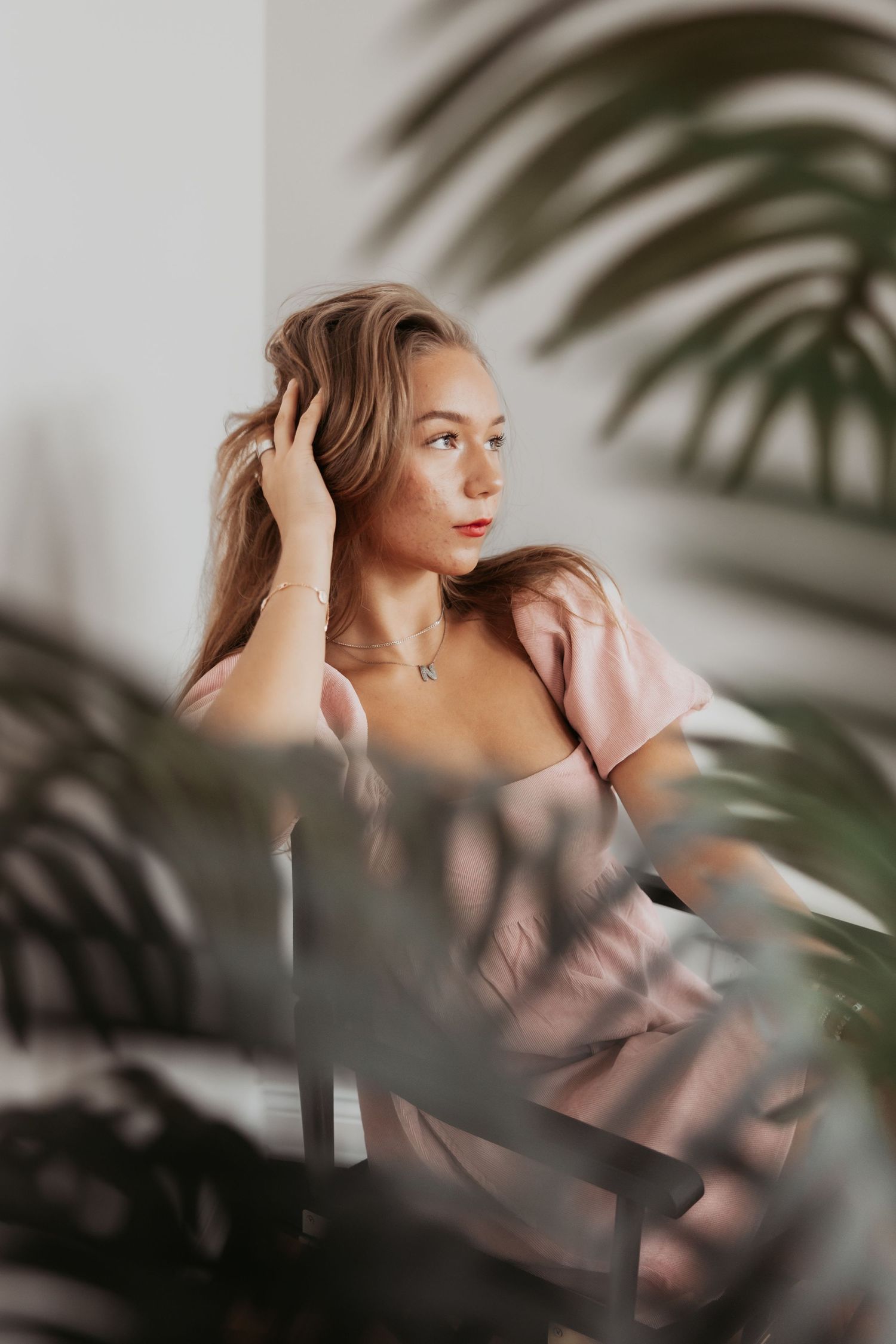 Romantic portrait through palm leaves featuring soft lighting and natural makeup.