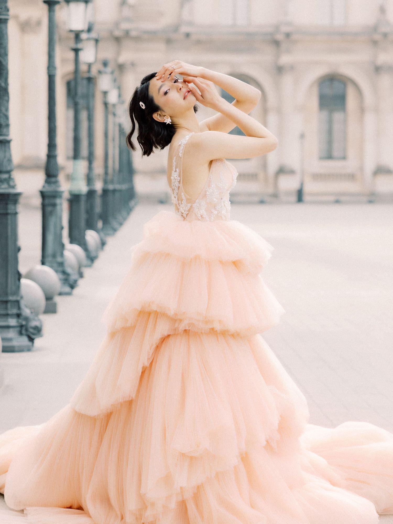 Ethereal peach layered tulle gown captured against historic European architecture.