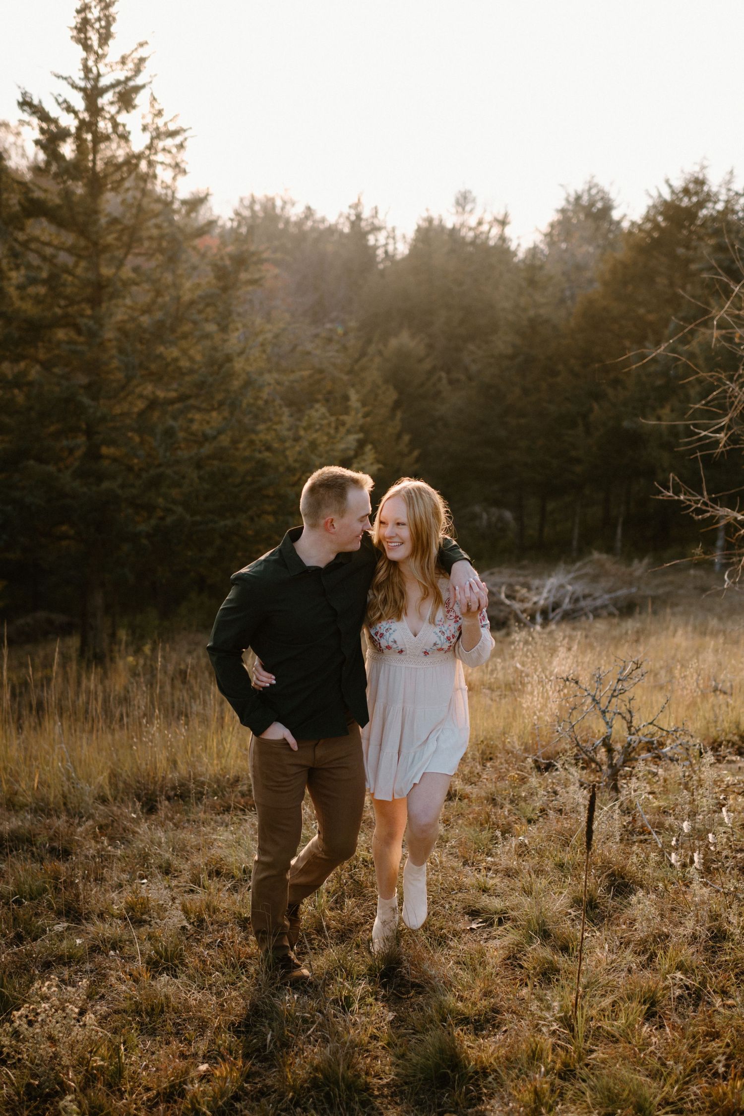 A couple shares a joyful moment in a sunlit autumn field.