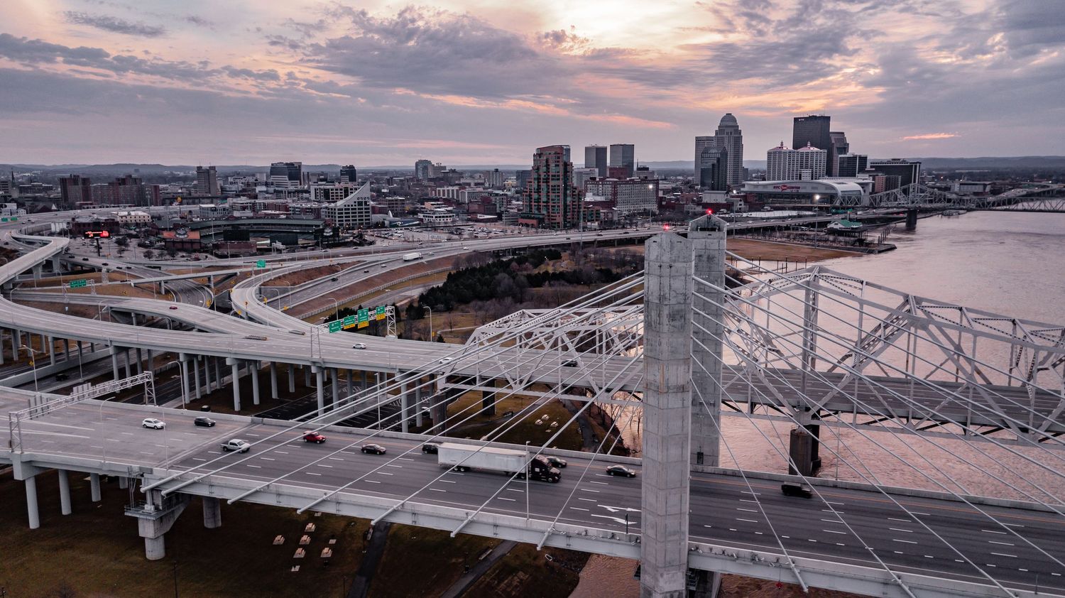Panoramic view of Cincinnati cityscape and bridges during golden hour.