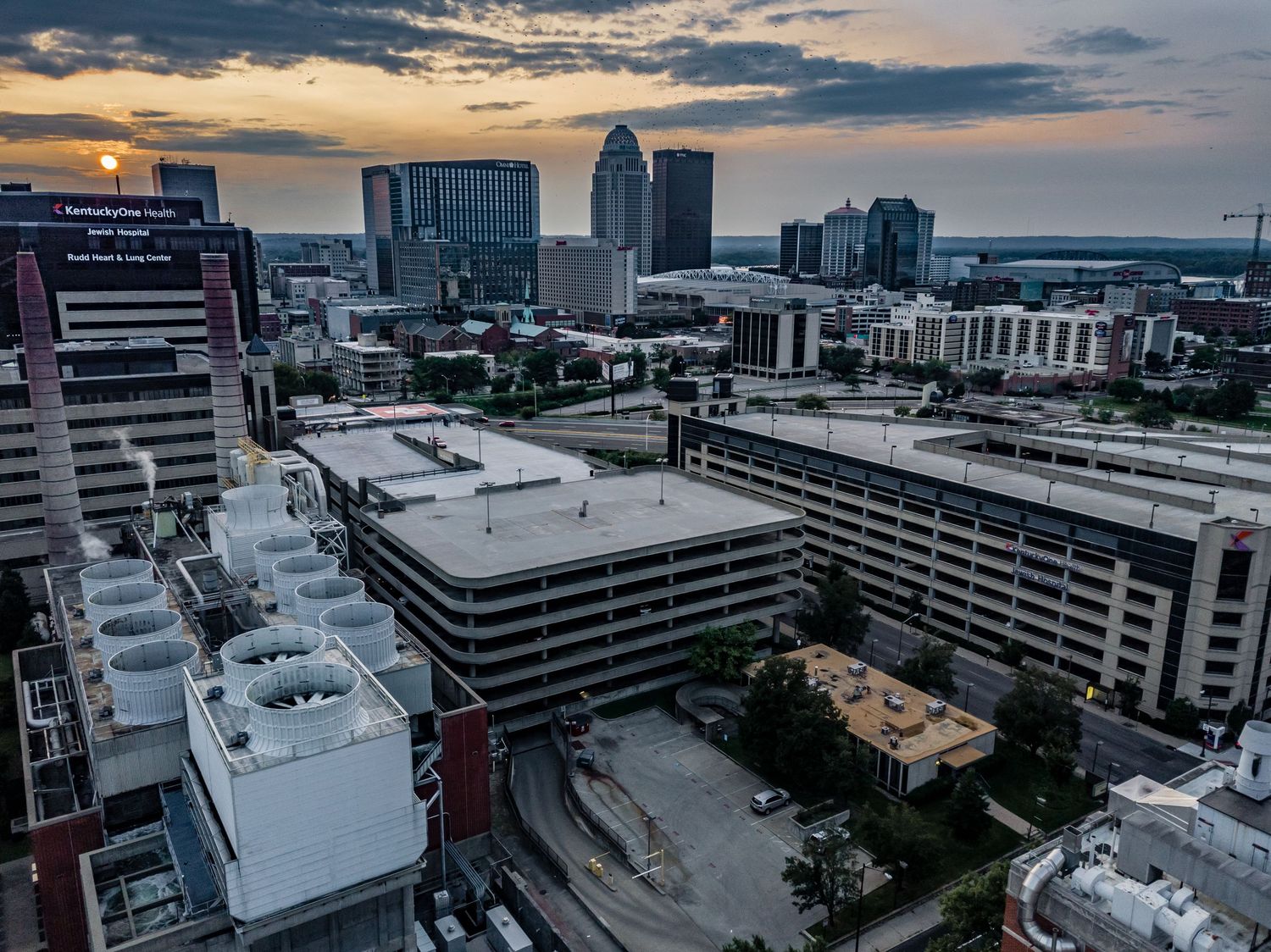 Downtown Louisville cityscape at dusk with modern buildings and parking structures.