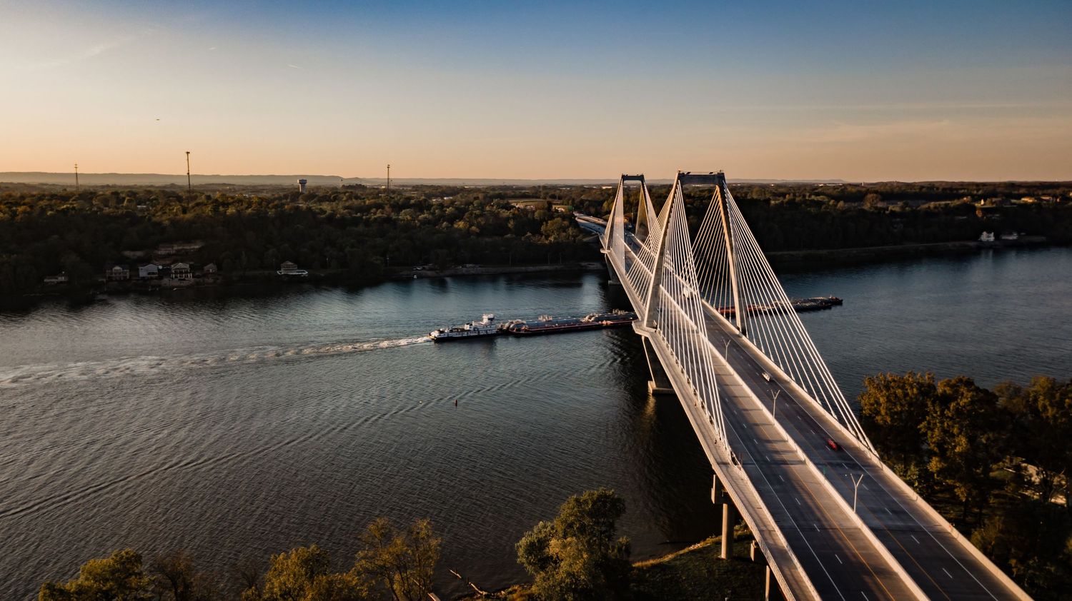 Panoramic skyline of Louisville featuring the Ohio River and bridges during sunset.