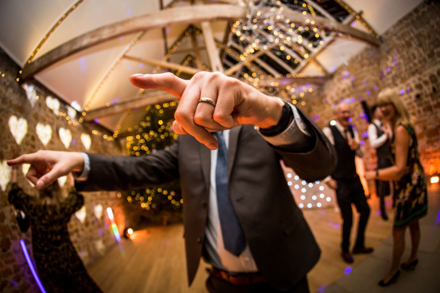 Wedding guests dance and celebrate on a rustic wooden dance floor at an evening reception.