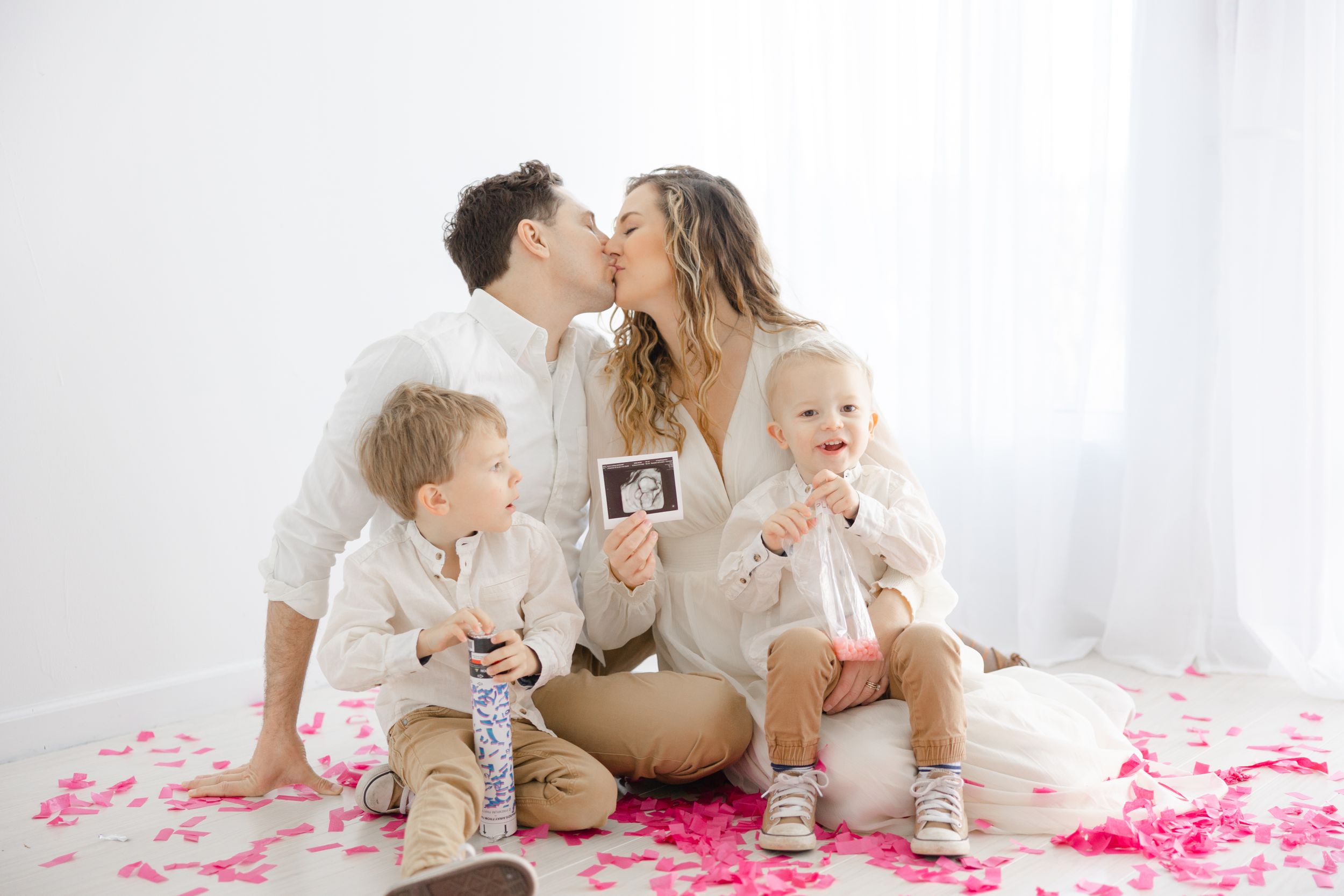 Mom and dad kissing holding image of 3D ultrasound.