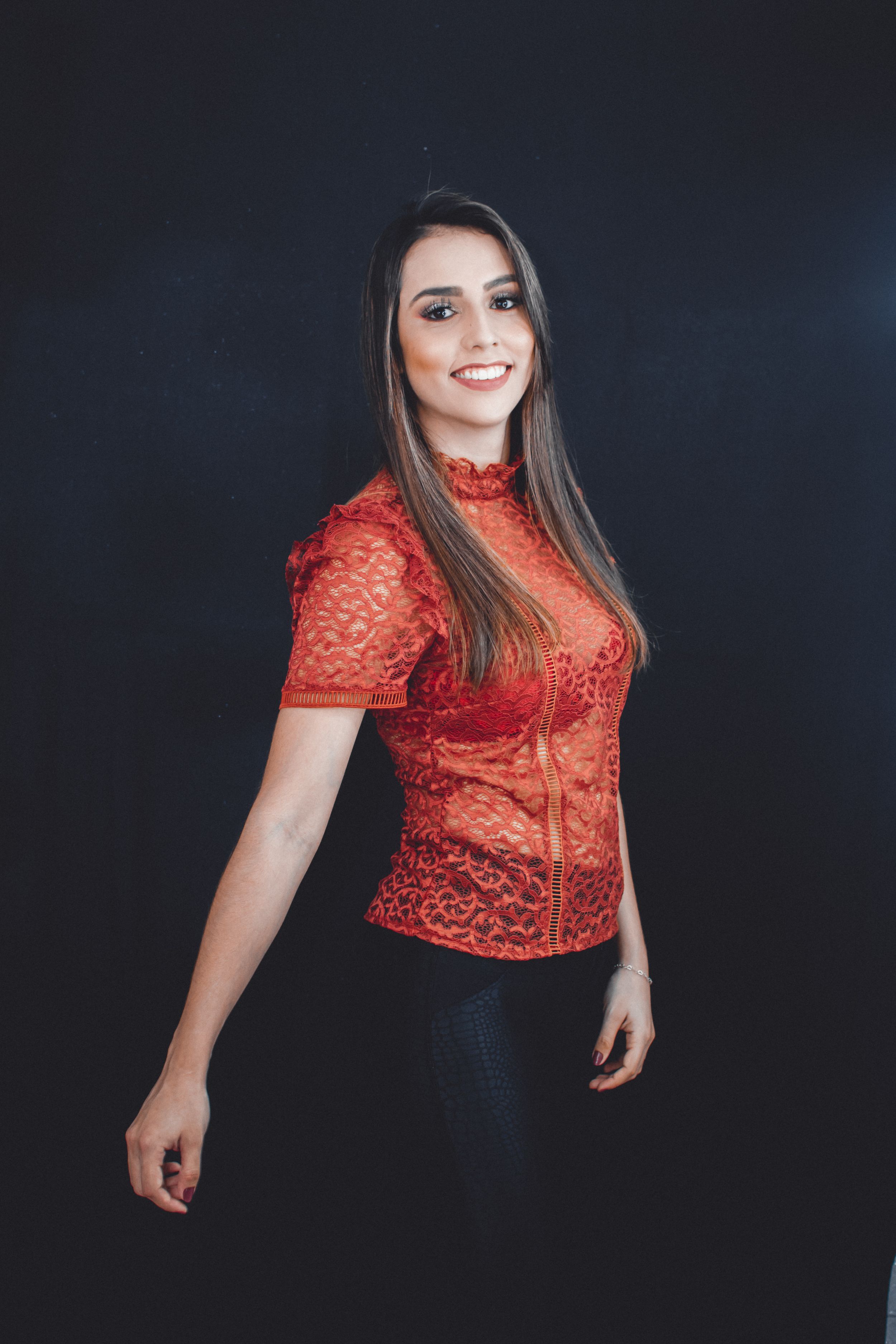 Fashion portraits in red lace top against dark background showcasing casual style.