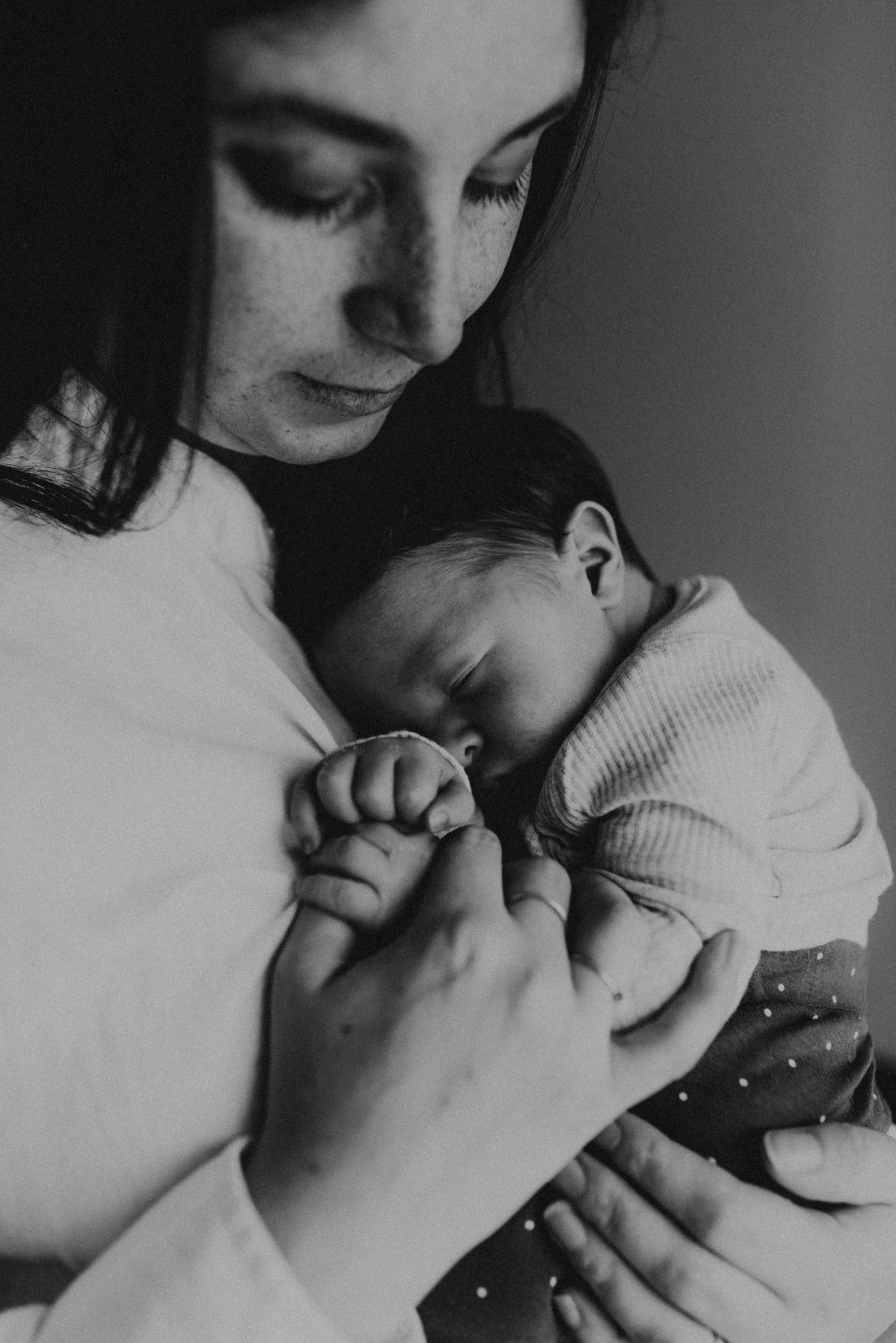 Black and white portrait of sleeping newborn being held tenderly.
