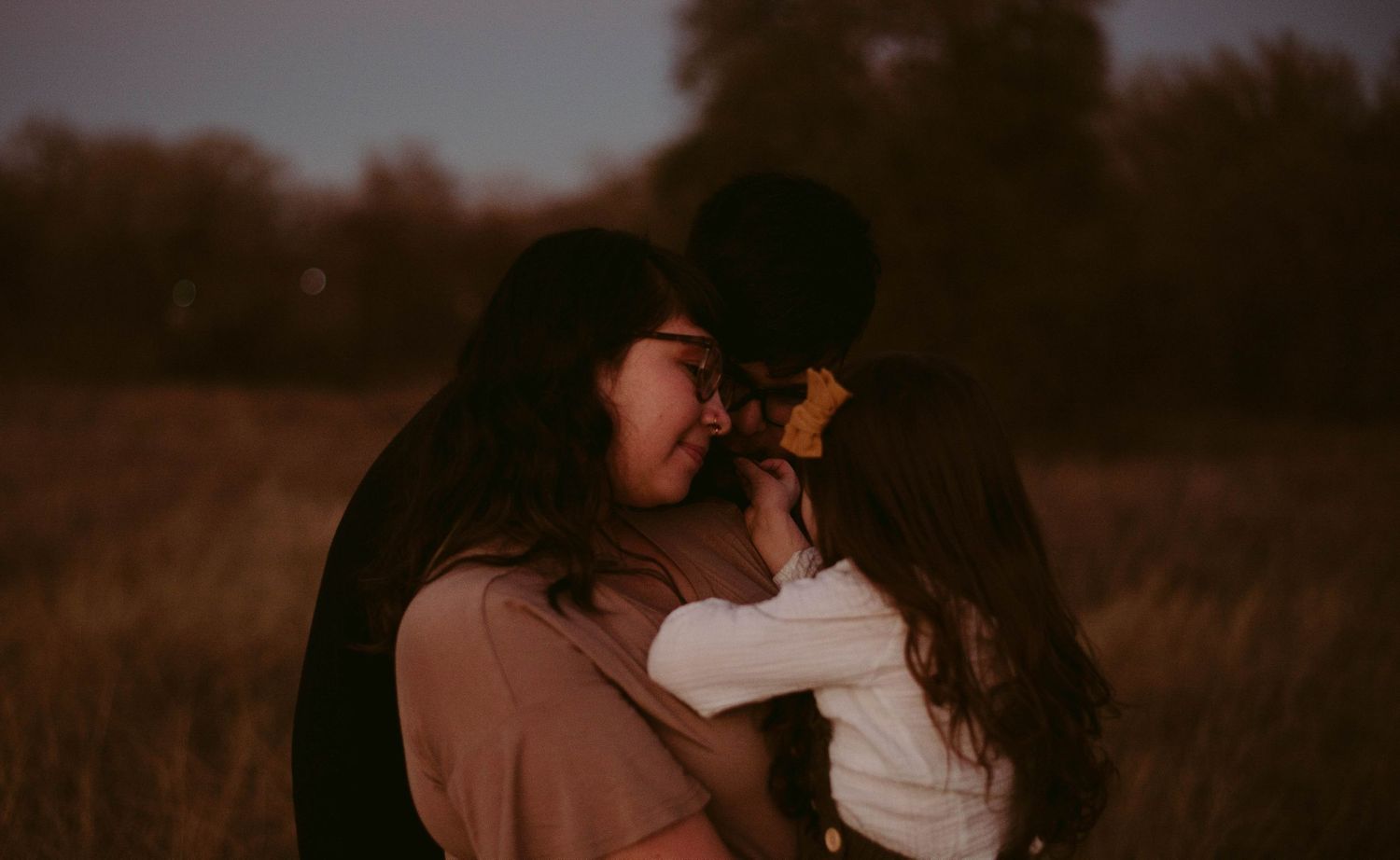 An intimate embrace shared between people in a field during golden hour.
