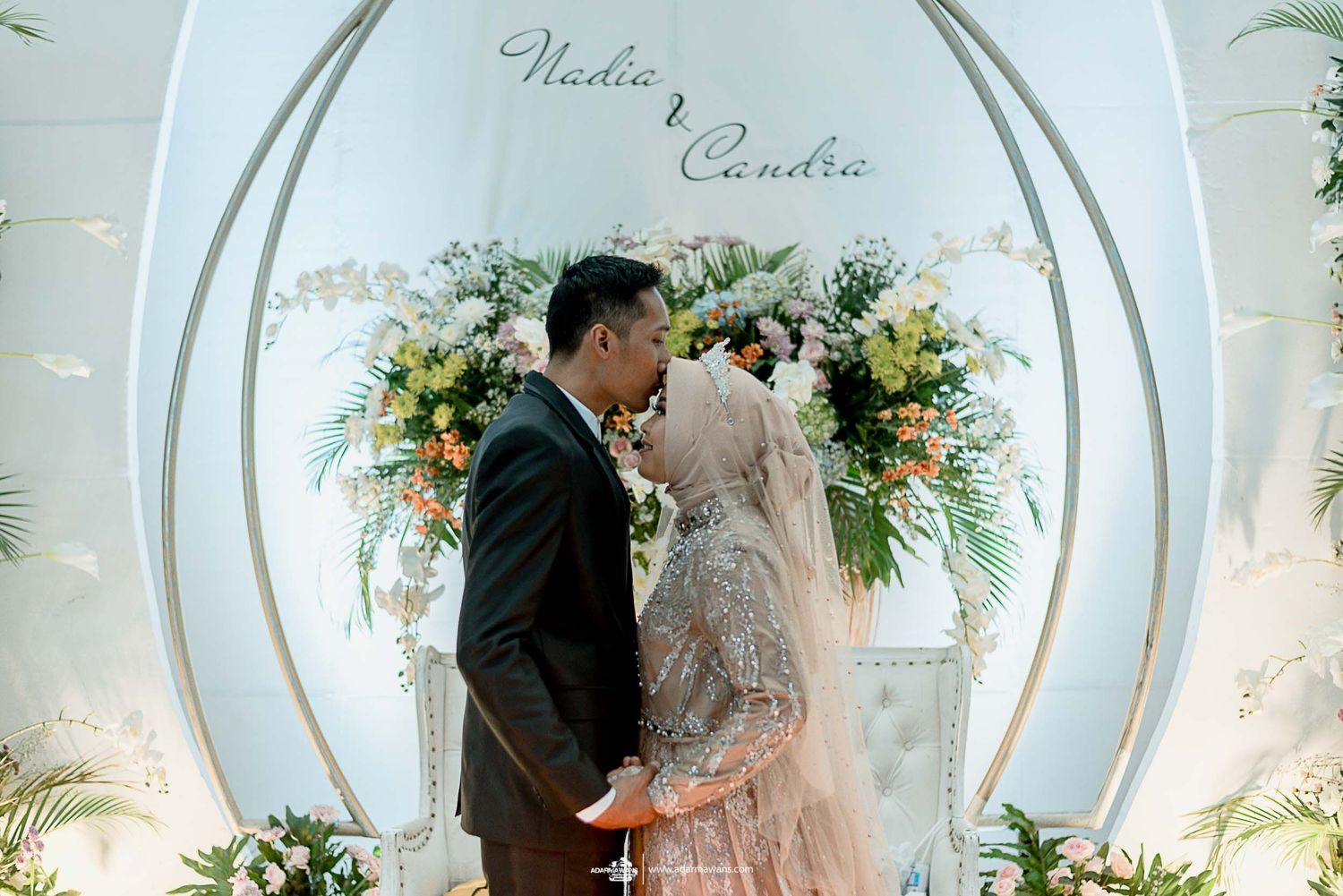 Artistic wedding photograph through oval archway with floral decorations.