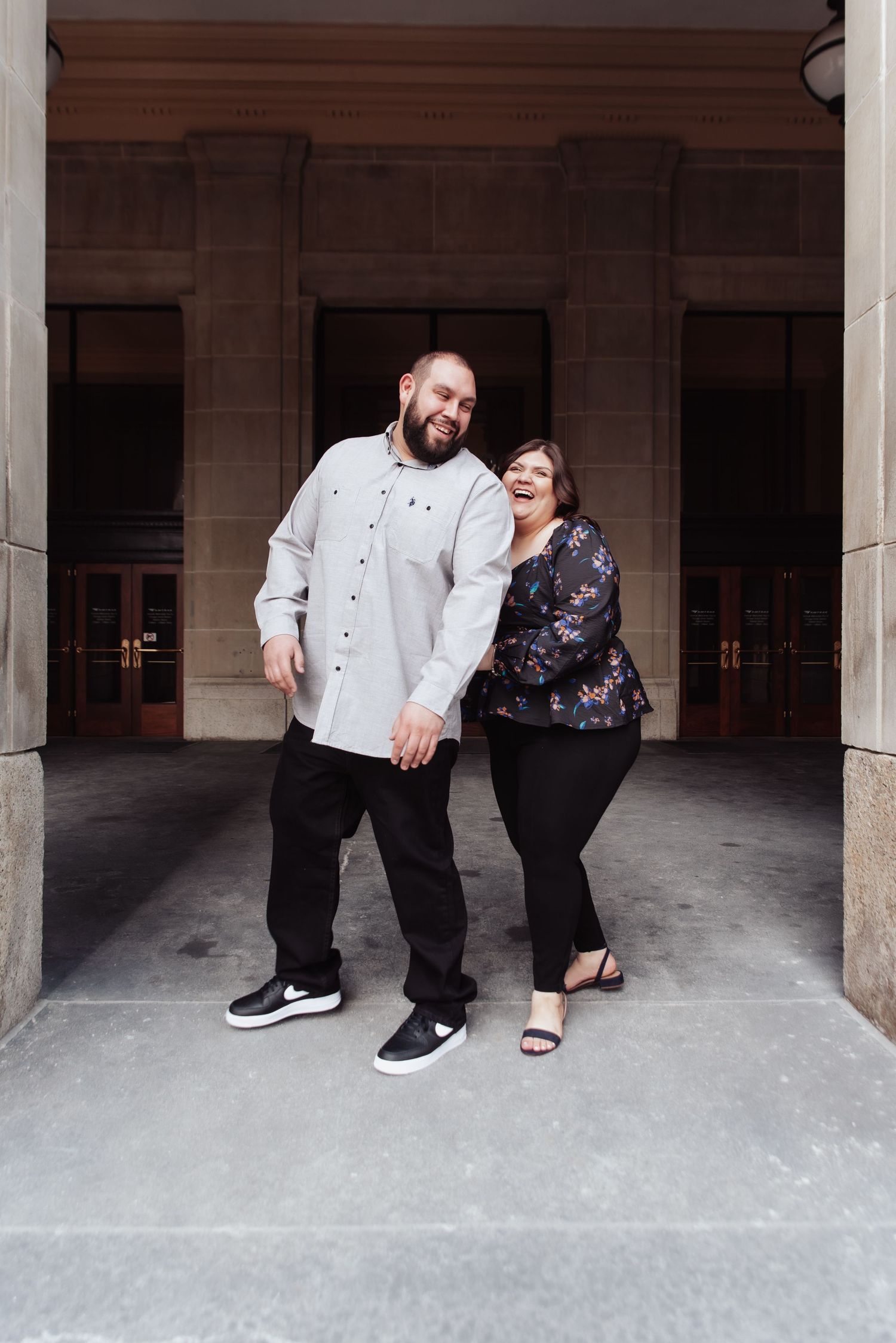 A casual portrait of a couple standing together under a stone archway.