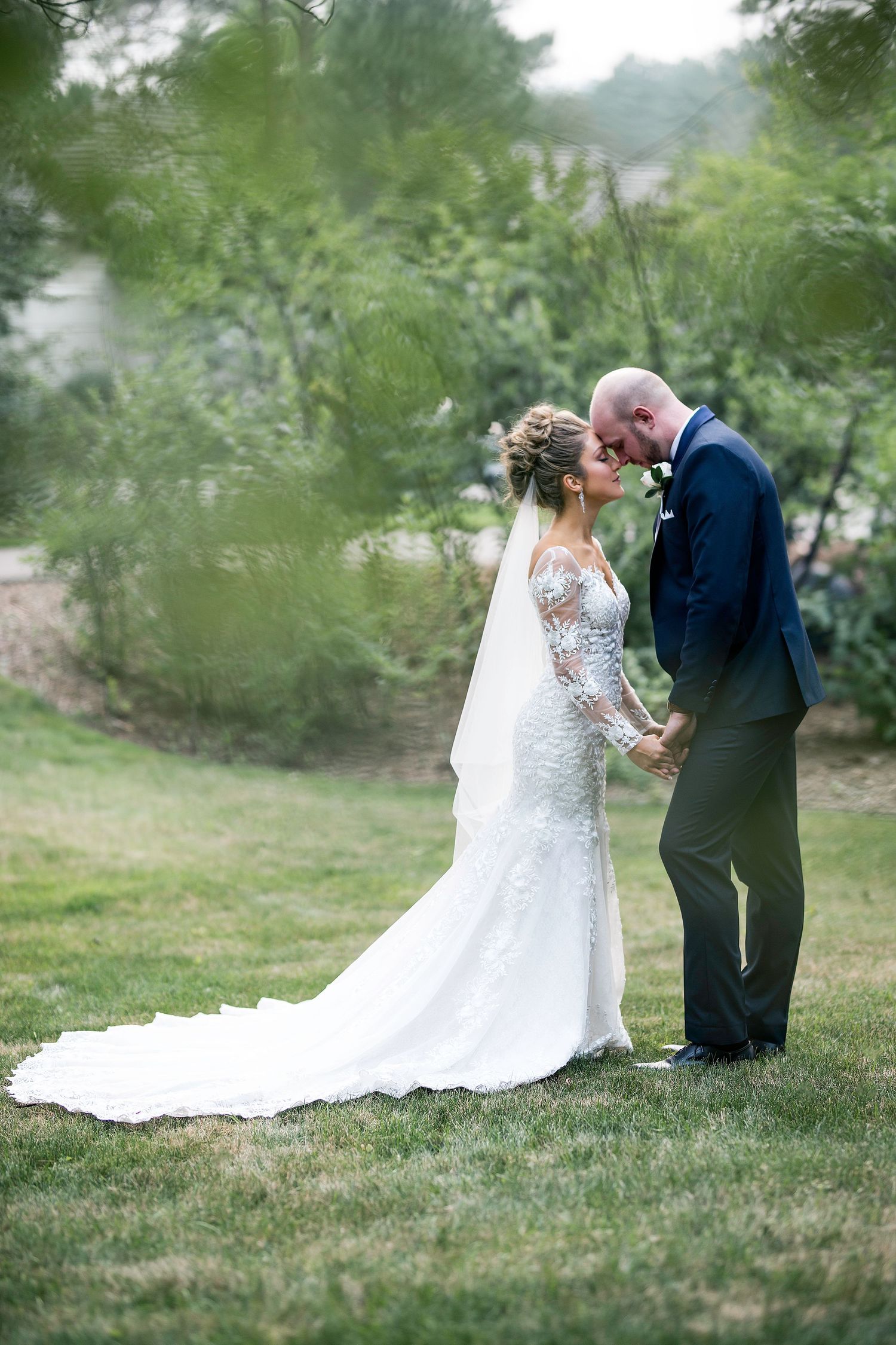 A romantic garden wedding portrait with soft focus greenery framing the scene.