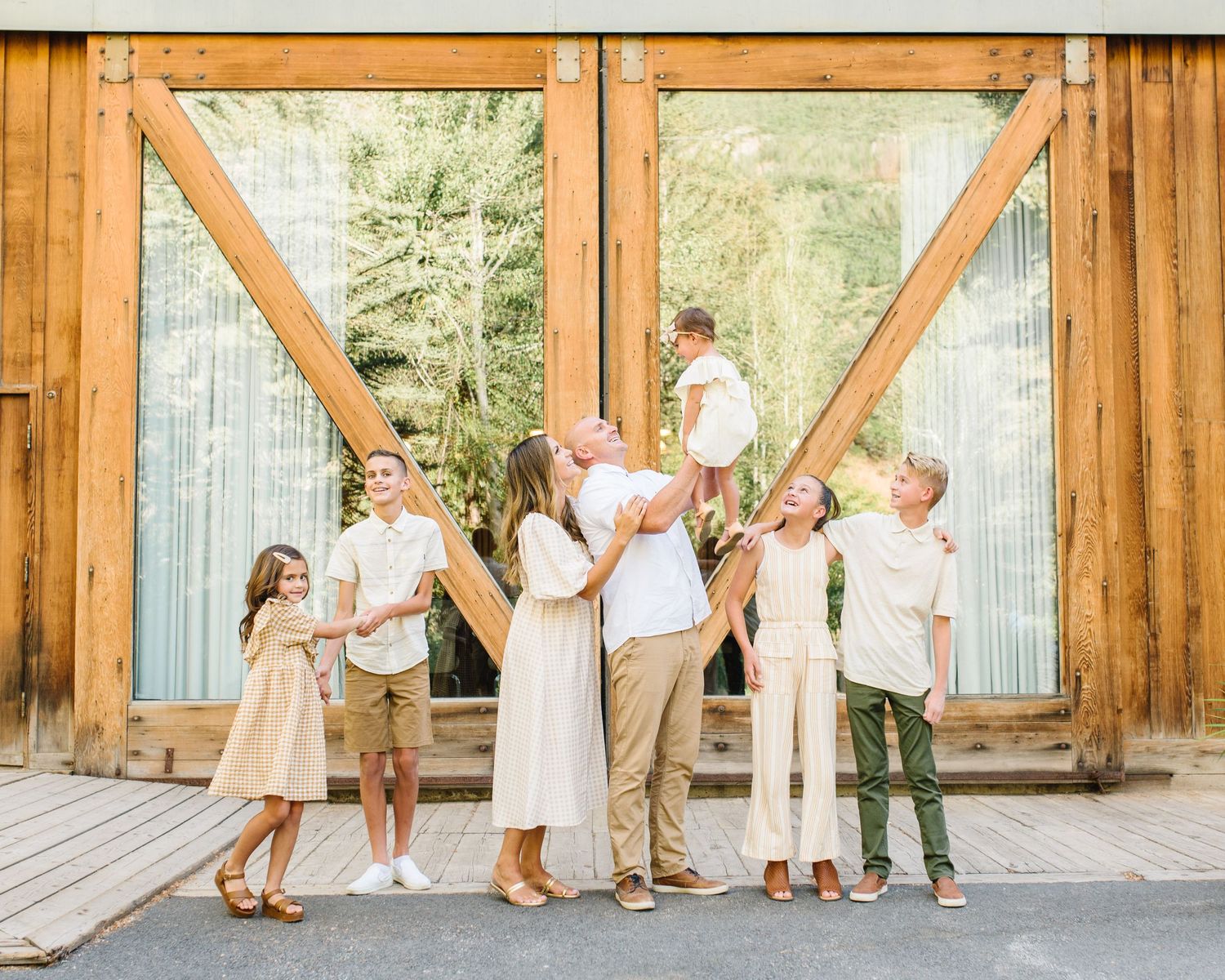 A family poses playfully in front of a rustic wooden barn door during a photo session.