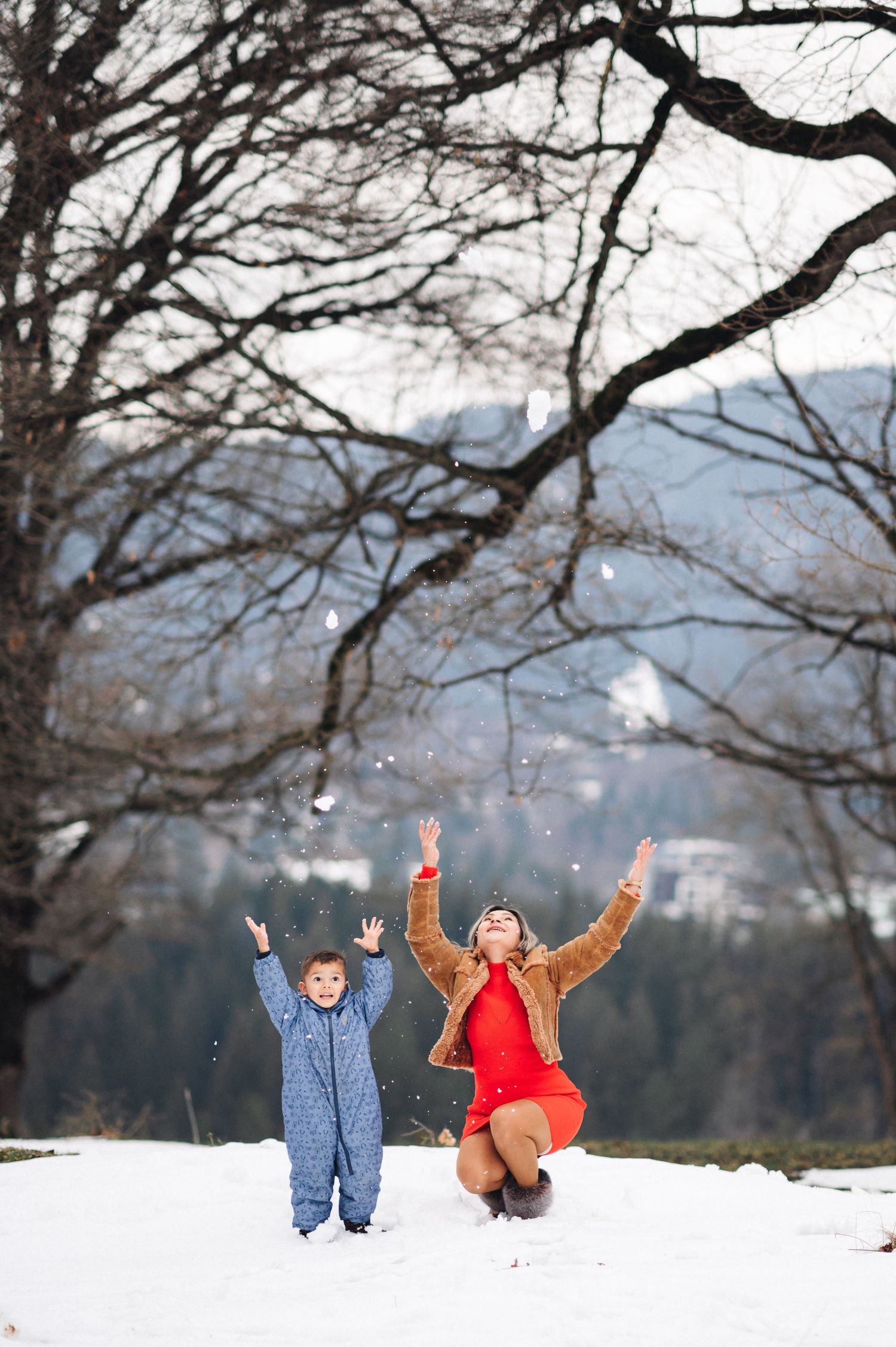 Joyful moment captured in the snow with mountains in the background.