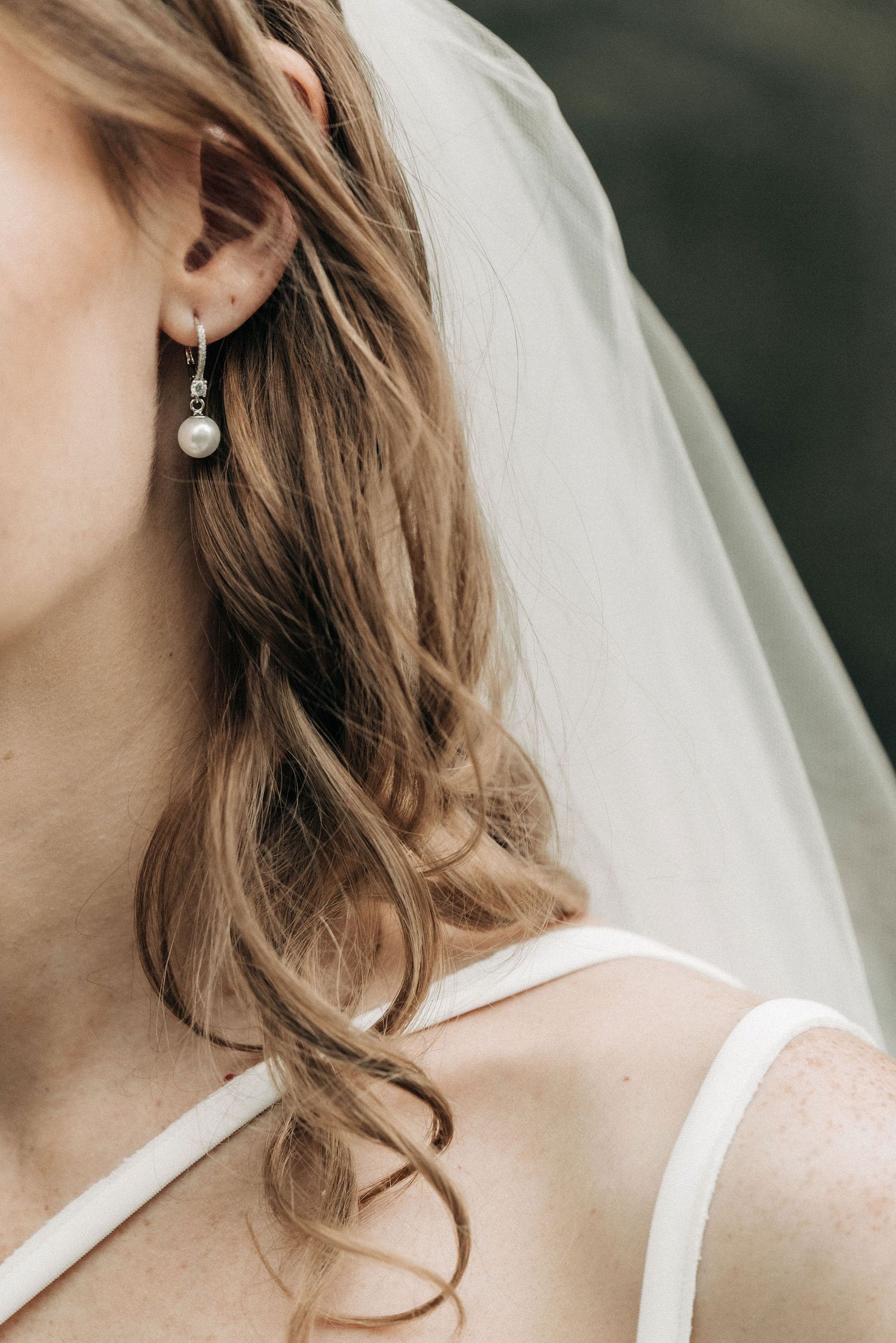 Pearl drop earring and flowing veil detail with soft curled hair.