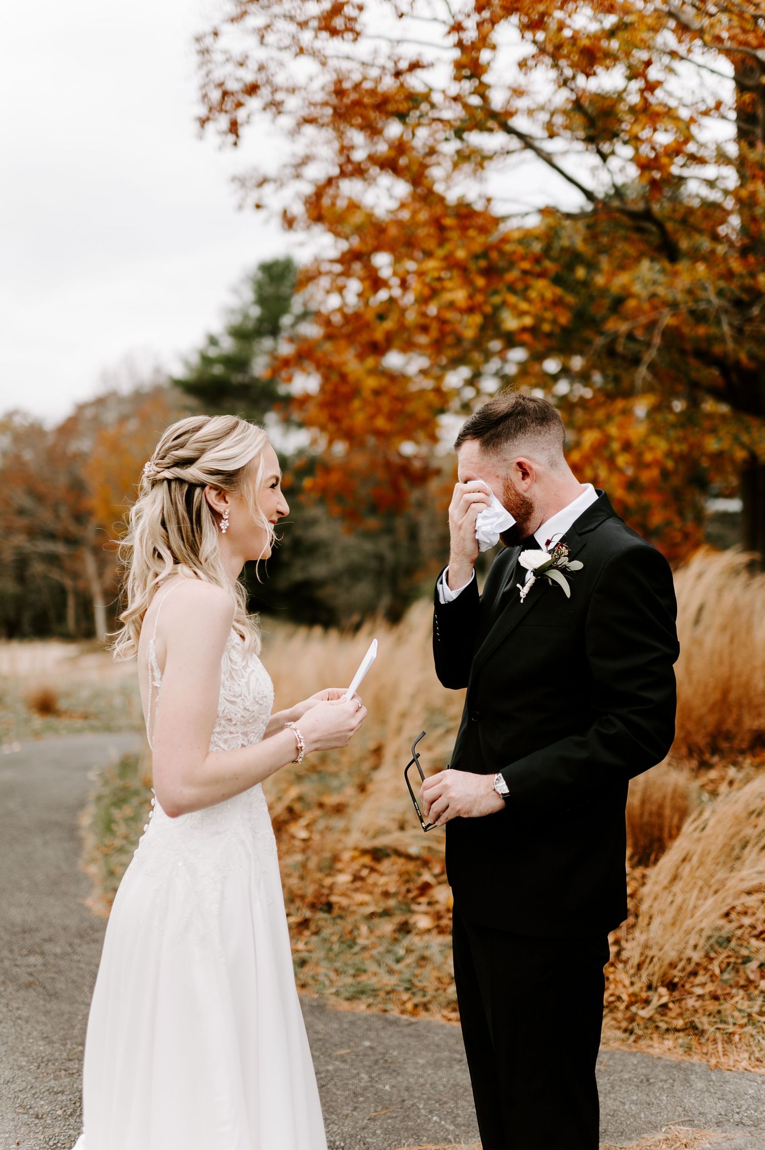 Wedding couple wiping away tears during their first look on a fall day.