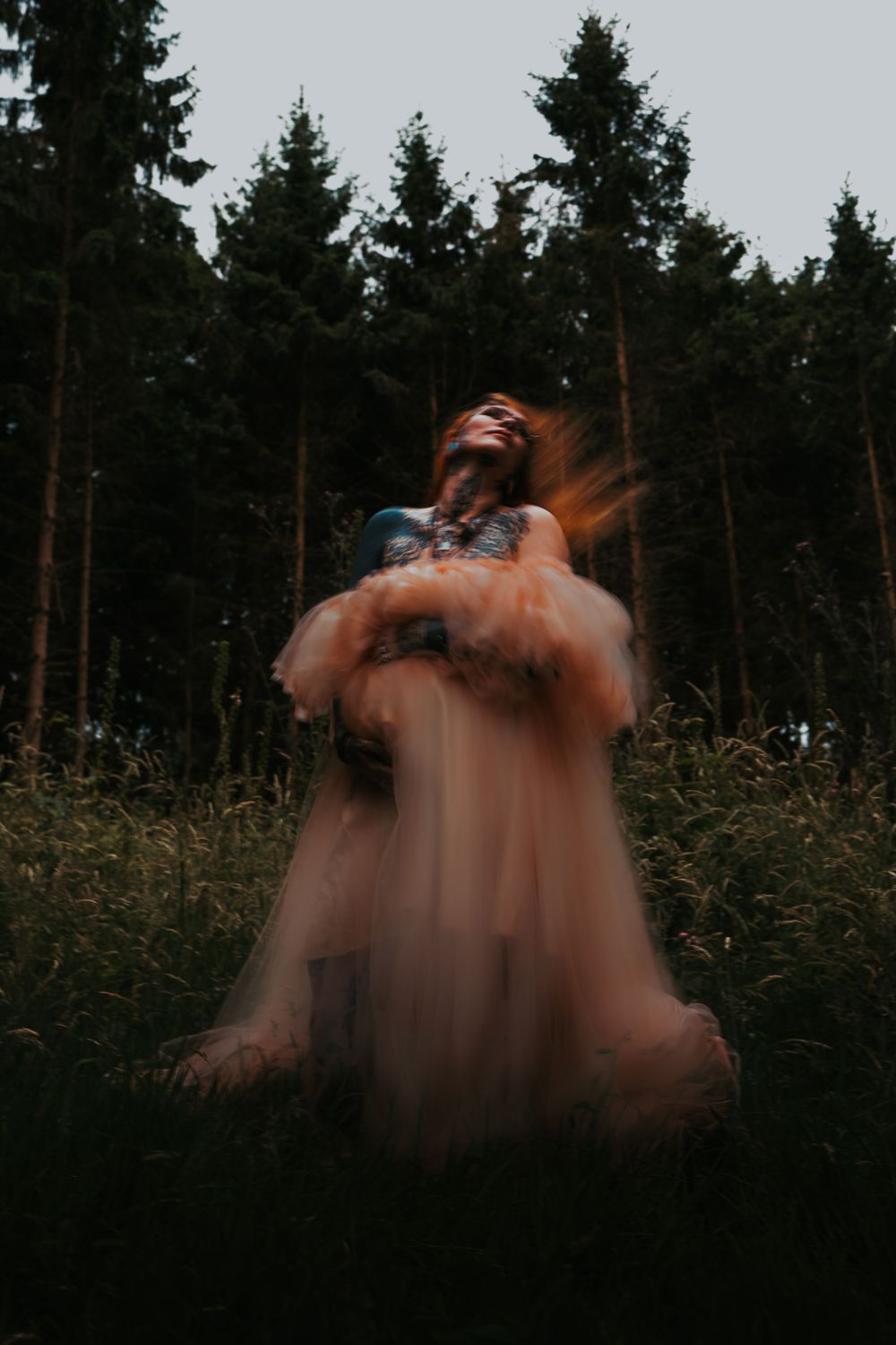 Blurred motion photography of a peach-colored dress in a twilight forest setting.