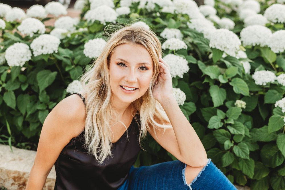 Portrait against white hydrangea bush with natural lighting.