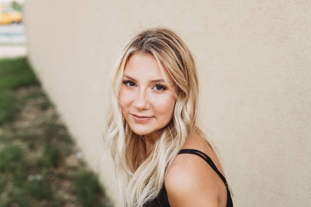 Casual portrait against neutral wall with warm lighting.