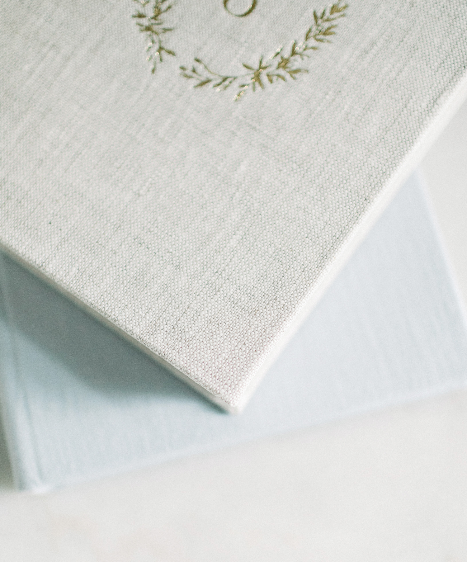 image of heirloom album in fine linen finish with gold debossing, stacked on top of grey one