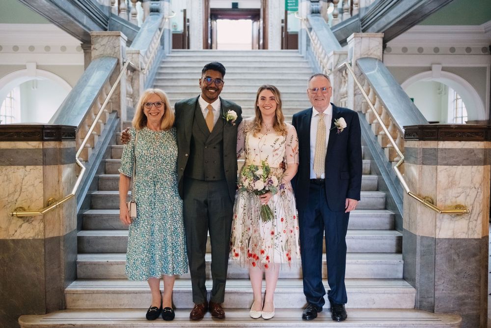 Small wedding group stands together on ornate stone staircase.