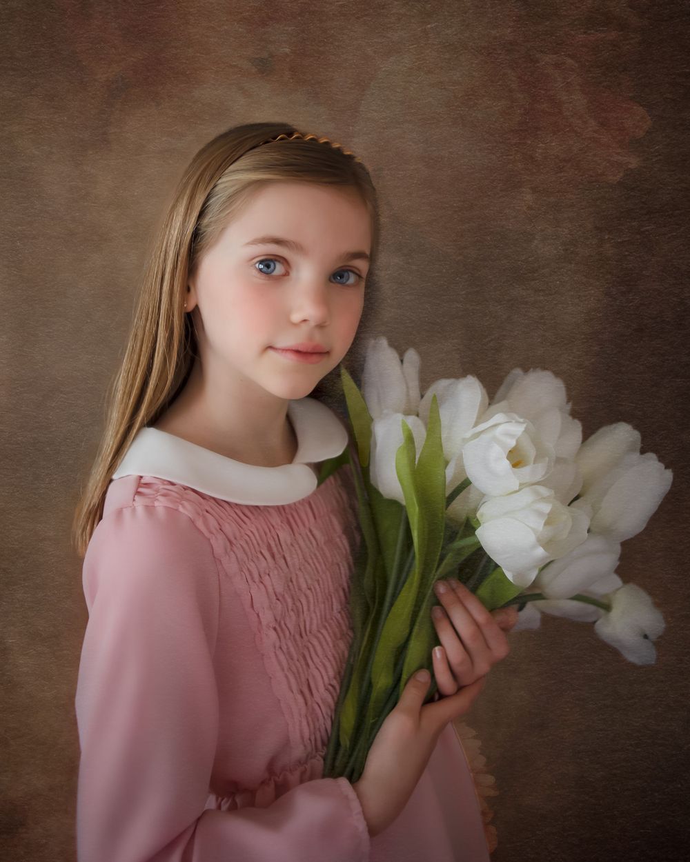 A portrait of someone in pink holding white tulips against a textured brown background.