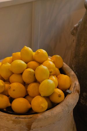 Fresh yellow lemons piled high in a rustic stone bowl.