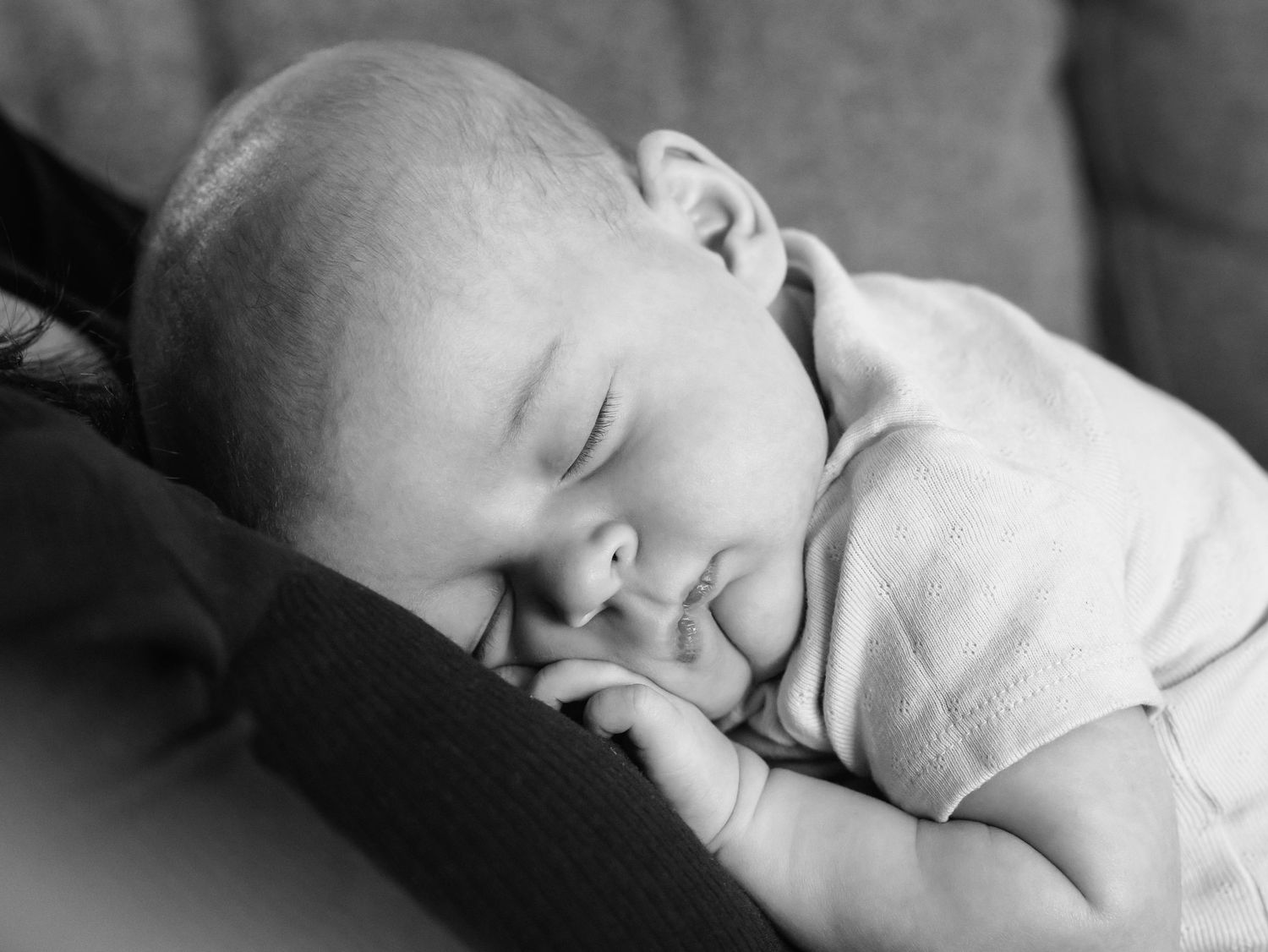 black and white close up of sleeping infant cuddling mama