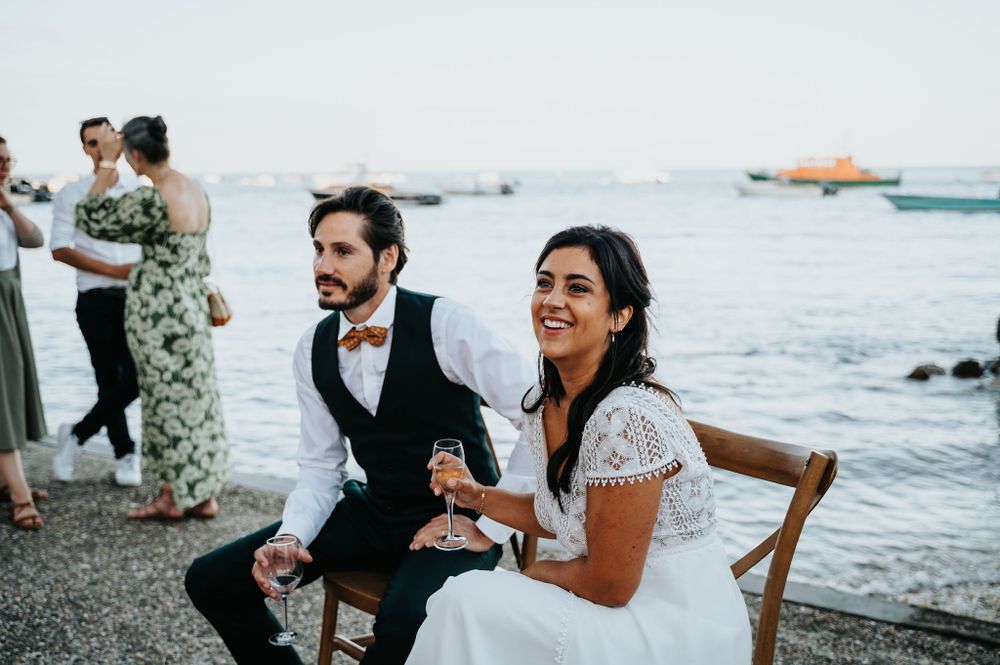 Wedding guests enjoy a beachside celebration with ocean waves in the background.