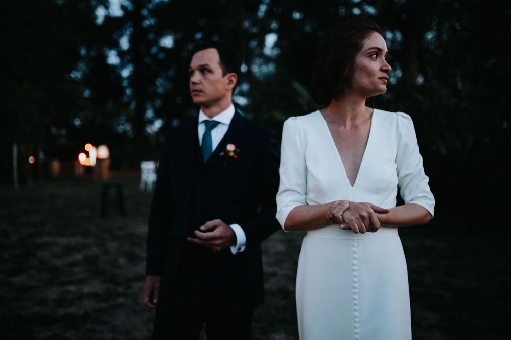A couple shares an intimate moment during their wedding reception at dusk.