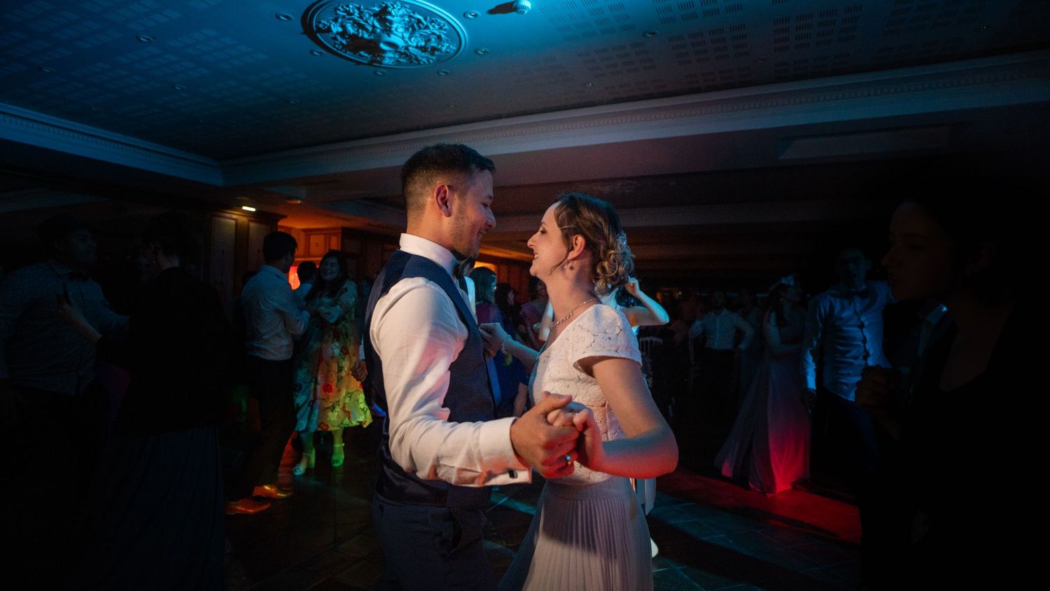 Romantic dance scene in dimly lit ballroom with blue lighting.