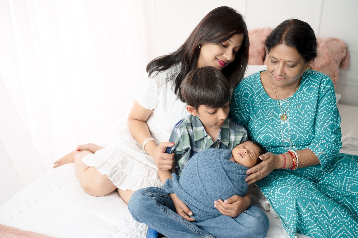 Three generations share loving moment during indoor family photo session.