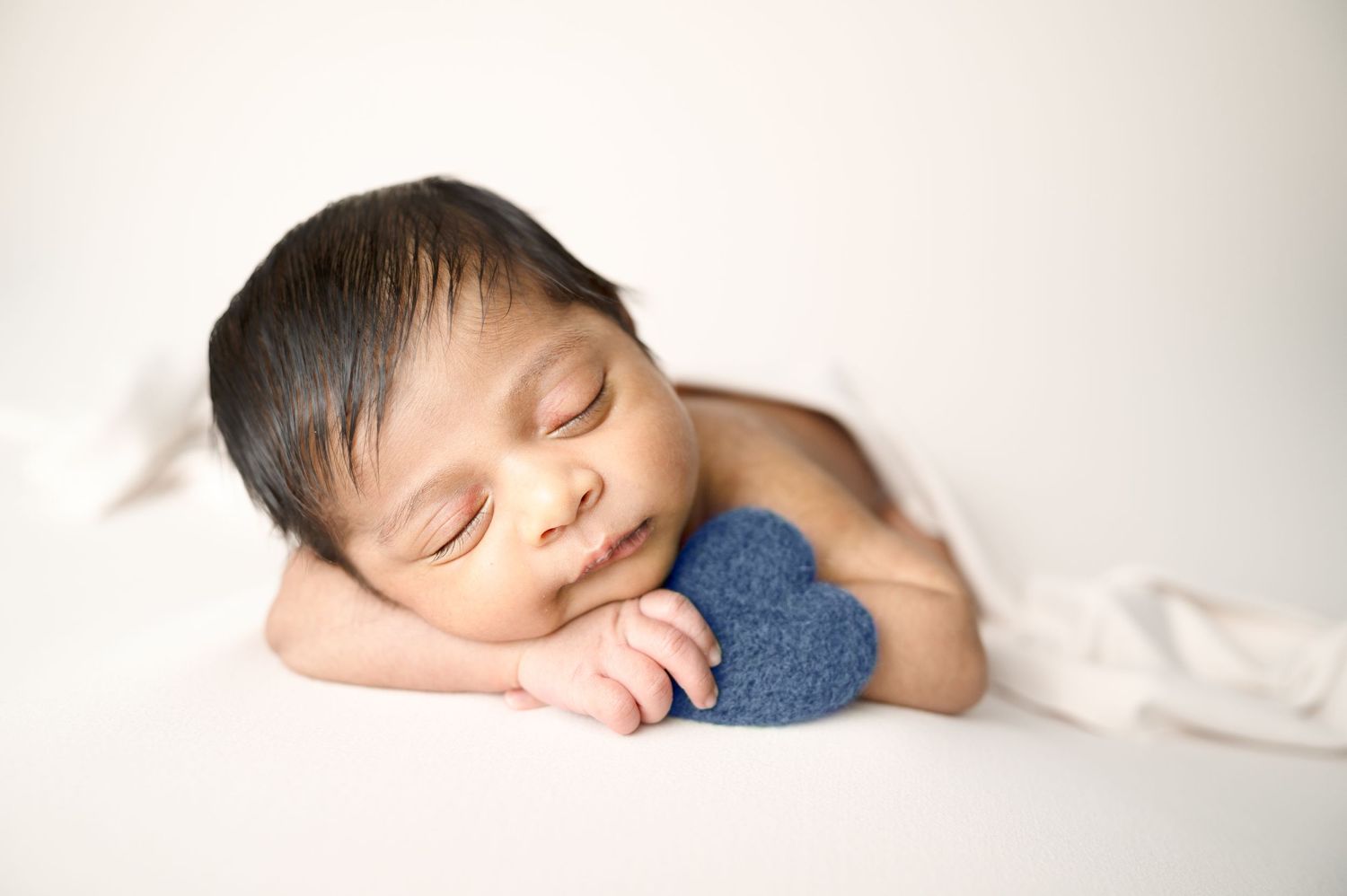 Serene sleeping newborn photos on white background with soft blue wrap.