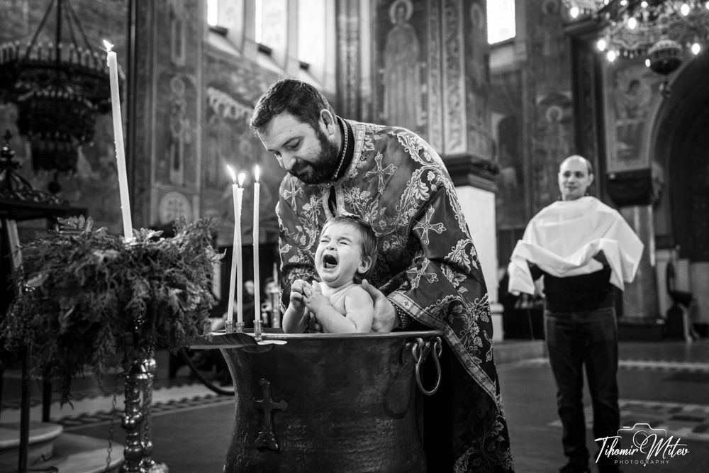 Отецът кращъва малко детенце и го полива с вода