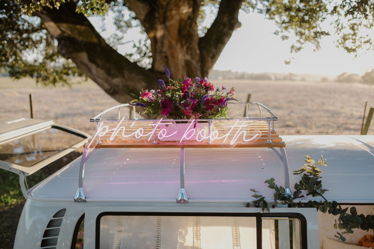 Vintage VW van with floral arrangements and 'Just Married' sign on top.