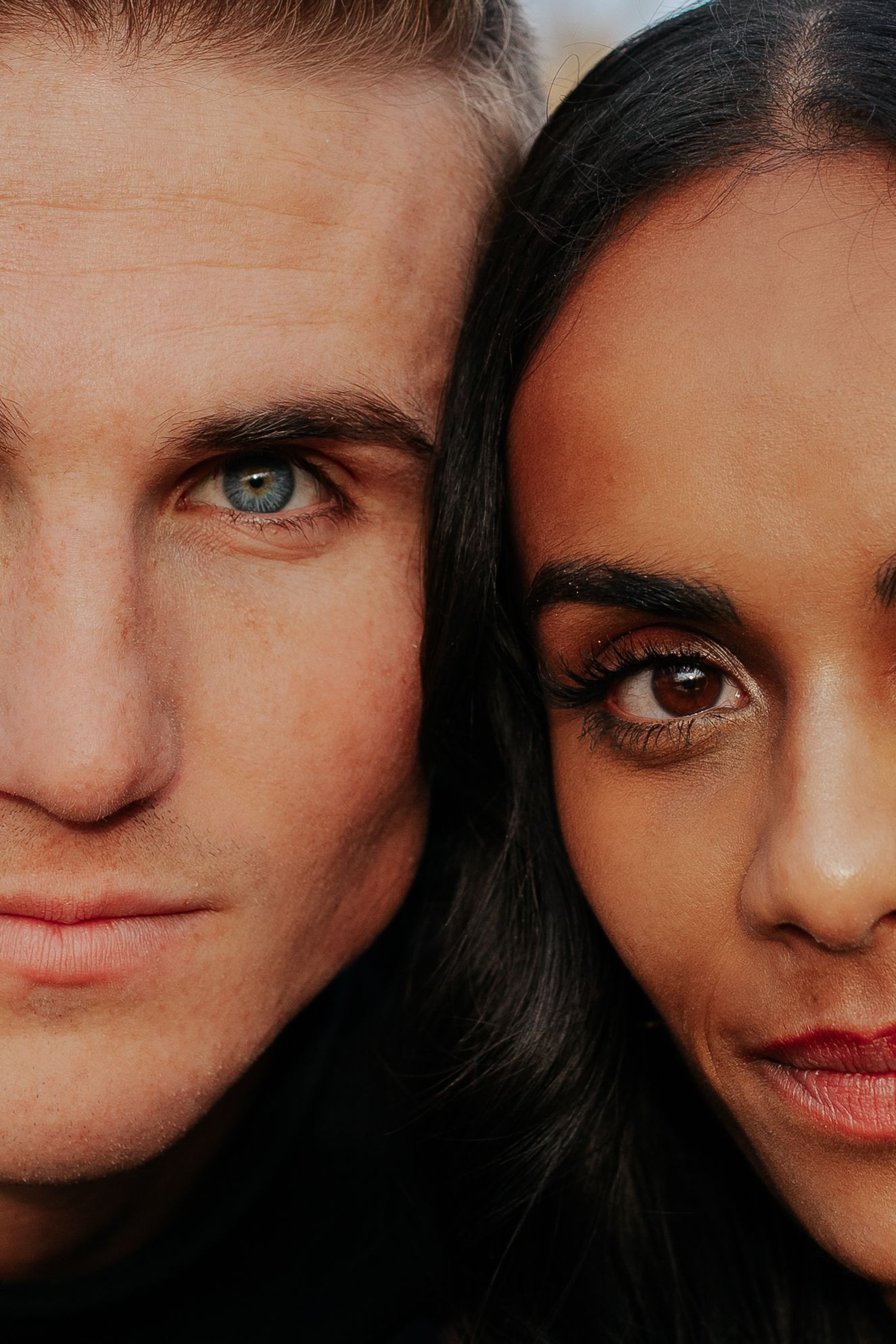 Close up portrait of two faces with contrasting features in dramatic lighting.
