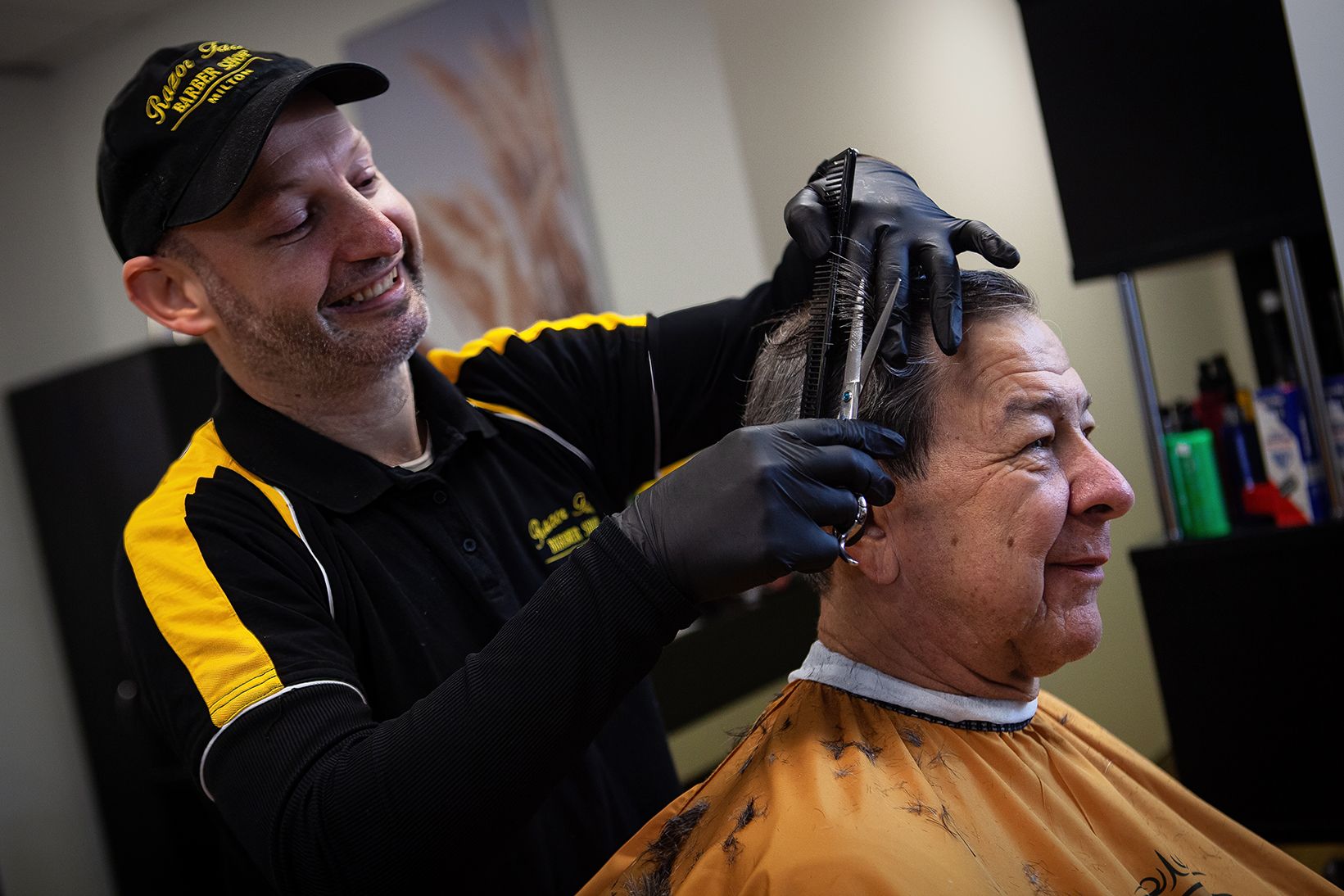 barber cutting a man's hair in a salon, both are smiling