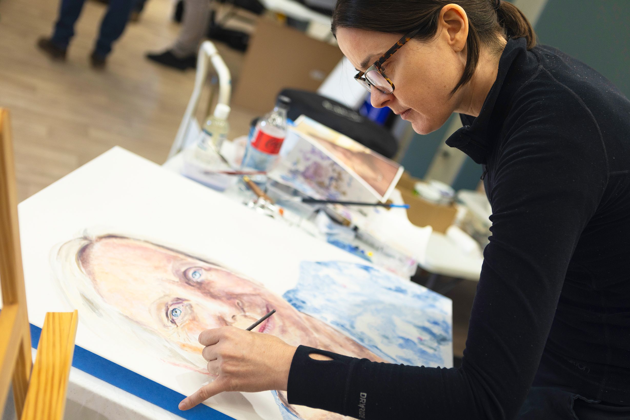 An artist paints a portrait with acrylic or oil paint onto a canvas