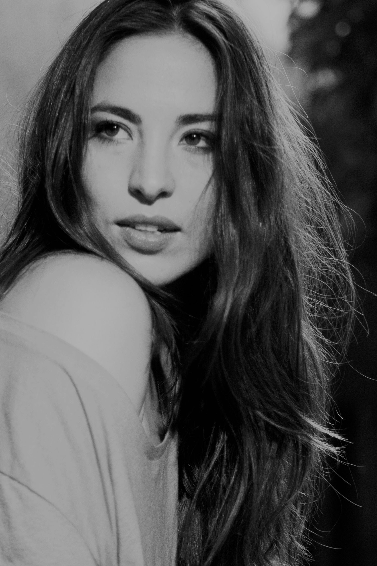 Black and white portrait of young woman with long dark hair looking over shoulder.