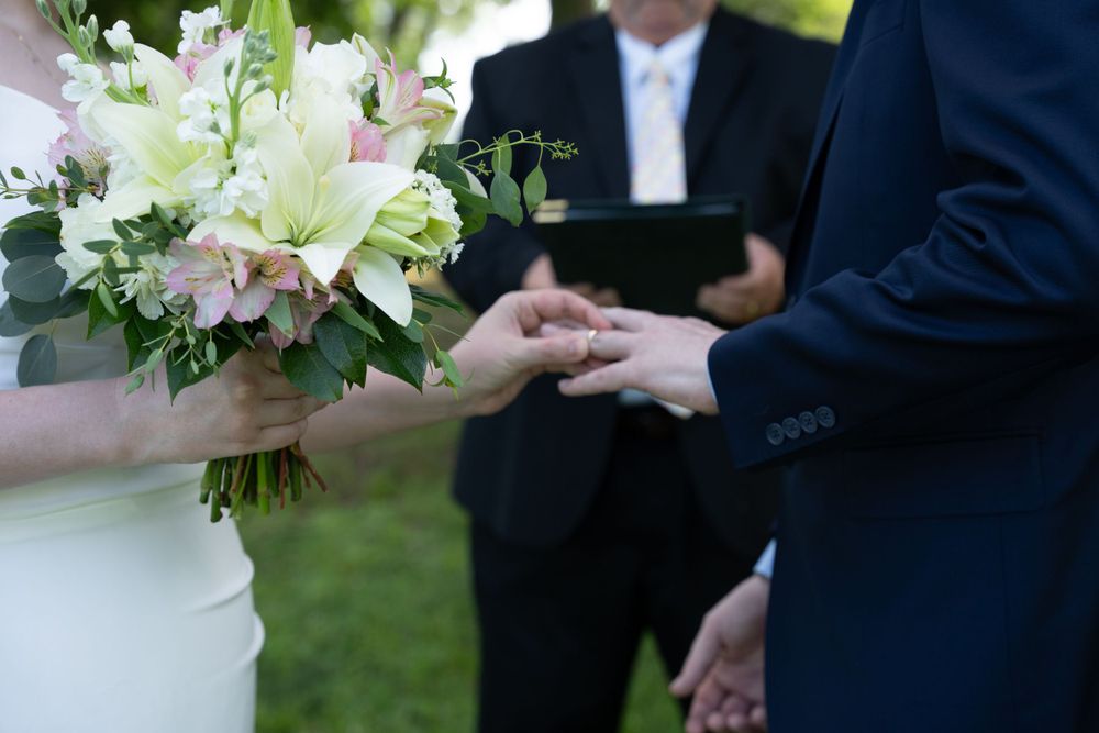Outdoor wedding photography ceremony. Couple holding hands with bouquet and wedding rings