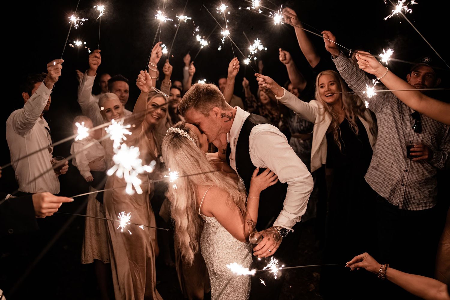 Wedding party celebrates with sparklers during nighttime send-off creating magical ambiance.