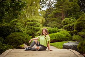 Person in casual wear relaxing on wooden bridge in Japanese garden setting.